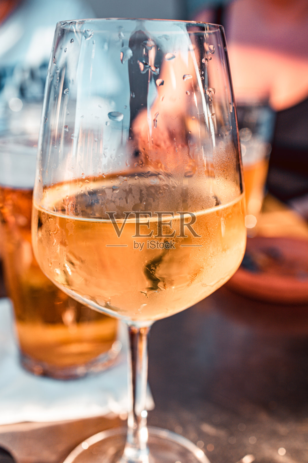 这是在米兰与朋友们一起享用的夏日开胃酒，配上白葡萄酒圣杯和几品脱的新鲜啤酒。零食作为背景。垂直切割。照片摄影图片