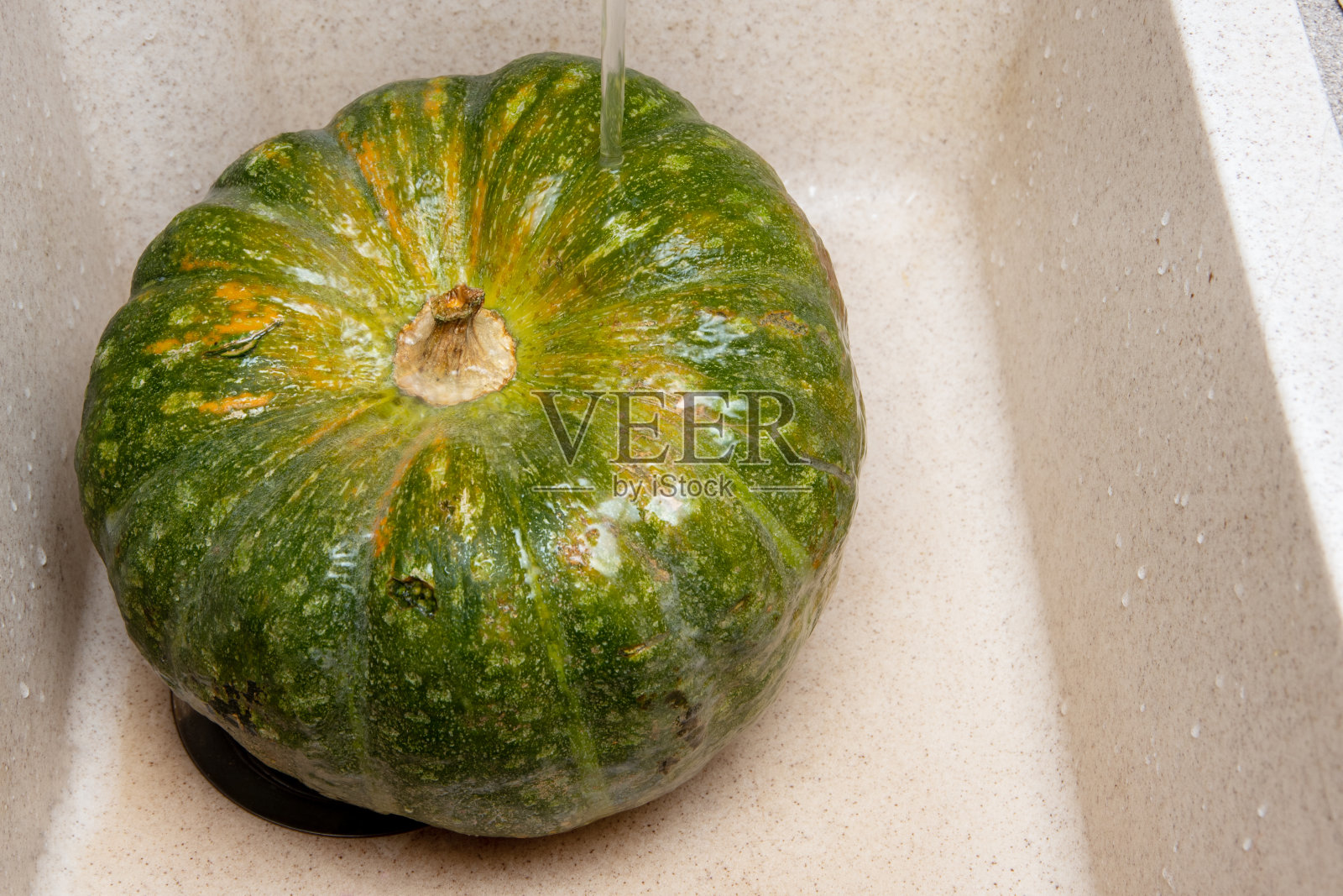 一个在水下洗过的青橙色南瓜的特写。素食主义的理念，健康营养，饮食照片摄影图片