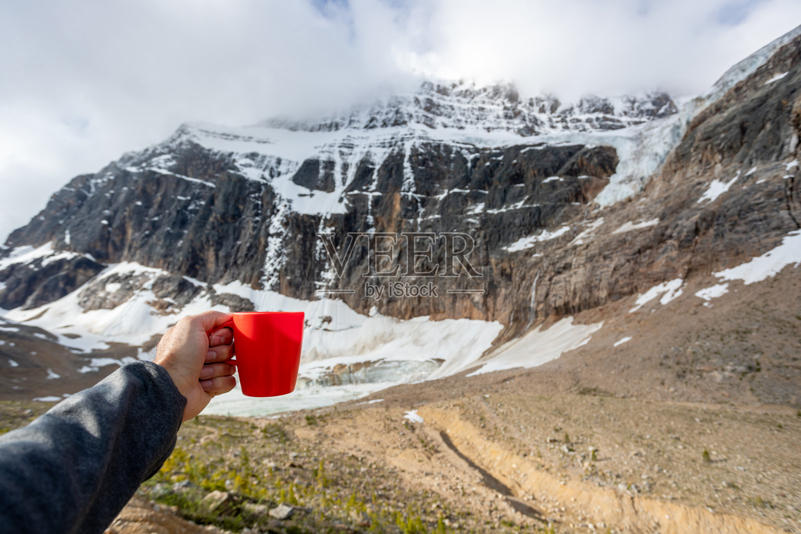 在加拿大阿尔伯塔省的伊迪丝卡维尔山，人手展示咖啡杯照片摄影图片