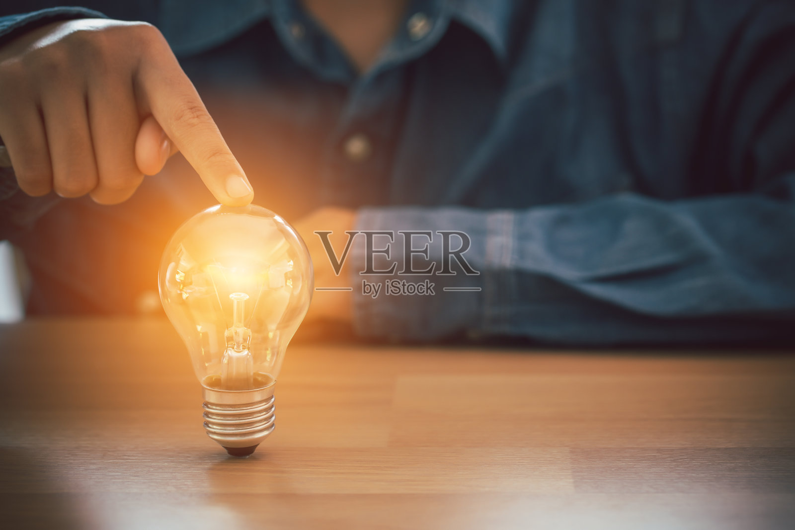 人的手触摸灯泡。商业、创新、创意的设计理念。照片摄影图片