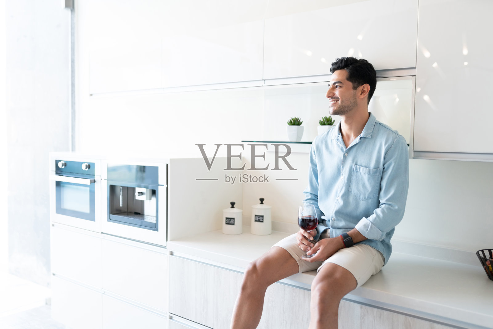 坐在厨房柜台上喝酒的男人照片摄影图片