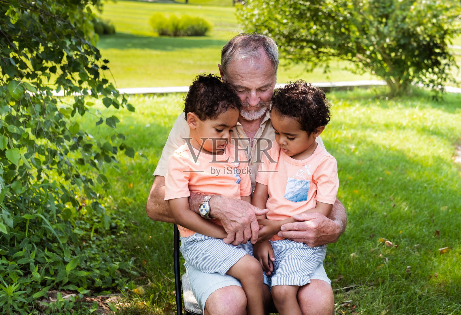 白人祖父和他的非裔双胞胎孙子聊天照片摄影图片