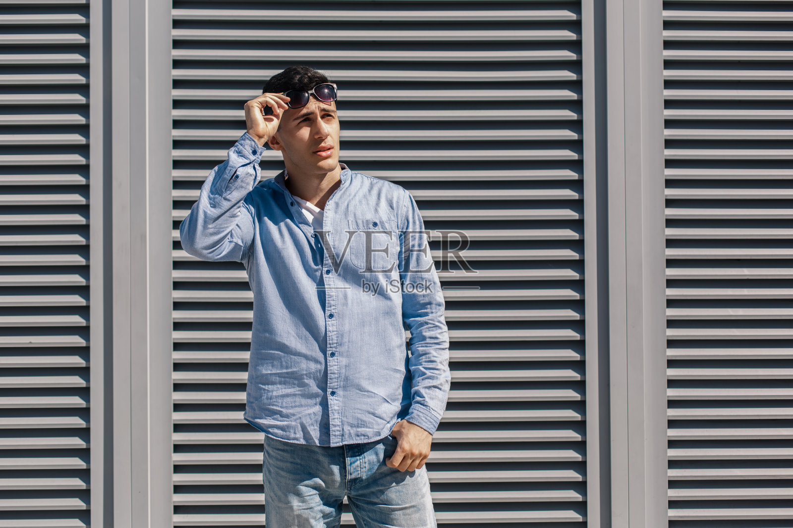 户外休闲。有型的家伙戴着太阳镜站在街上斜眼看一边照片摄影图片