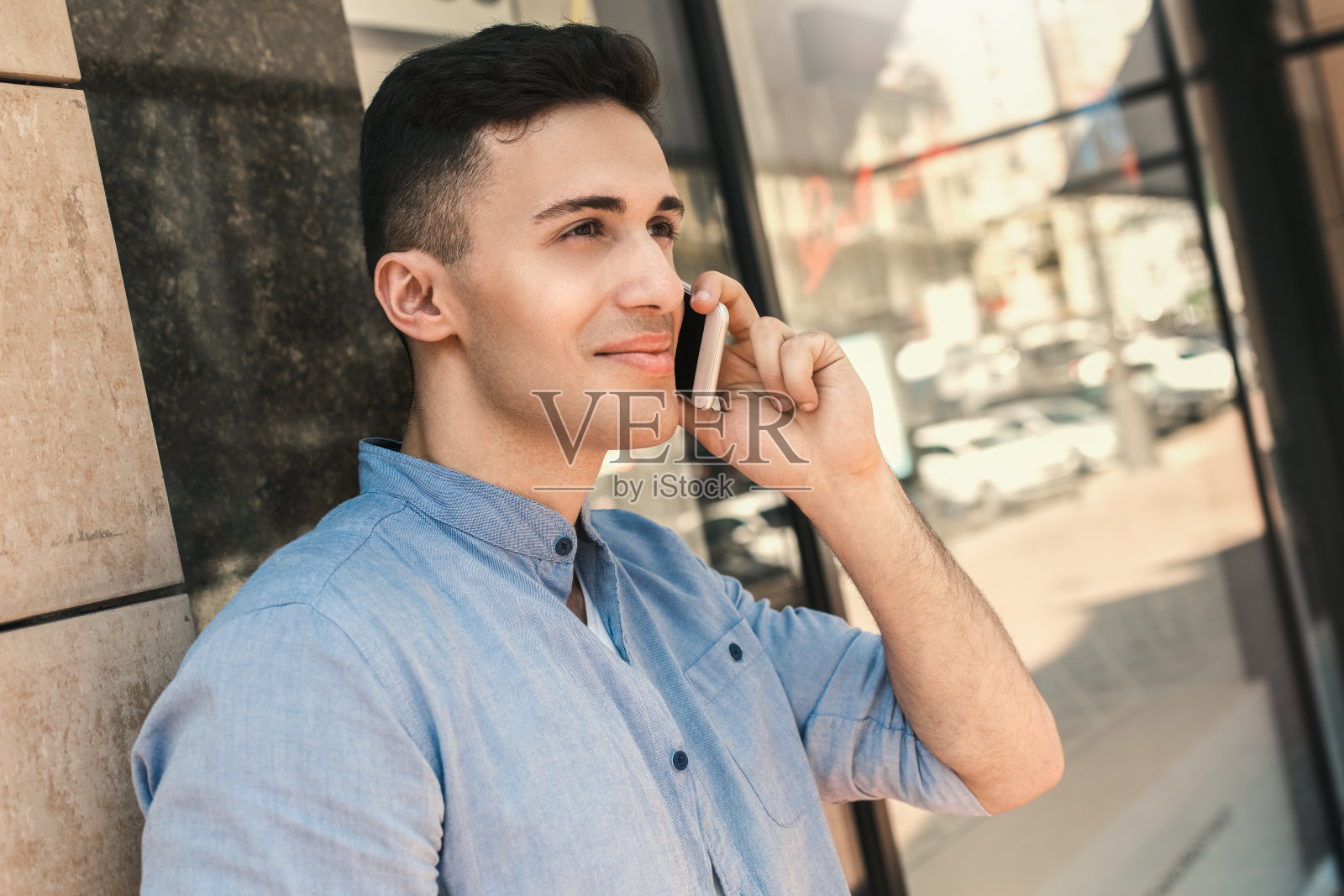 户外休闲。时尚的家伙站在街上靠在墙上接听电话快乐的特写照片摄影图片