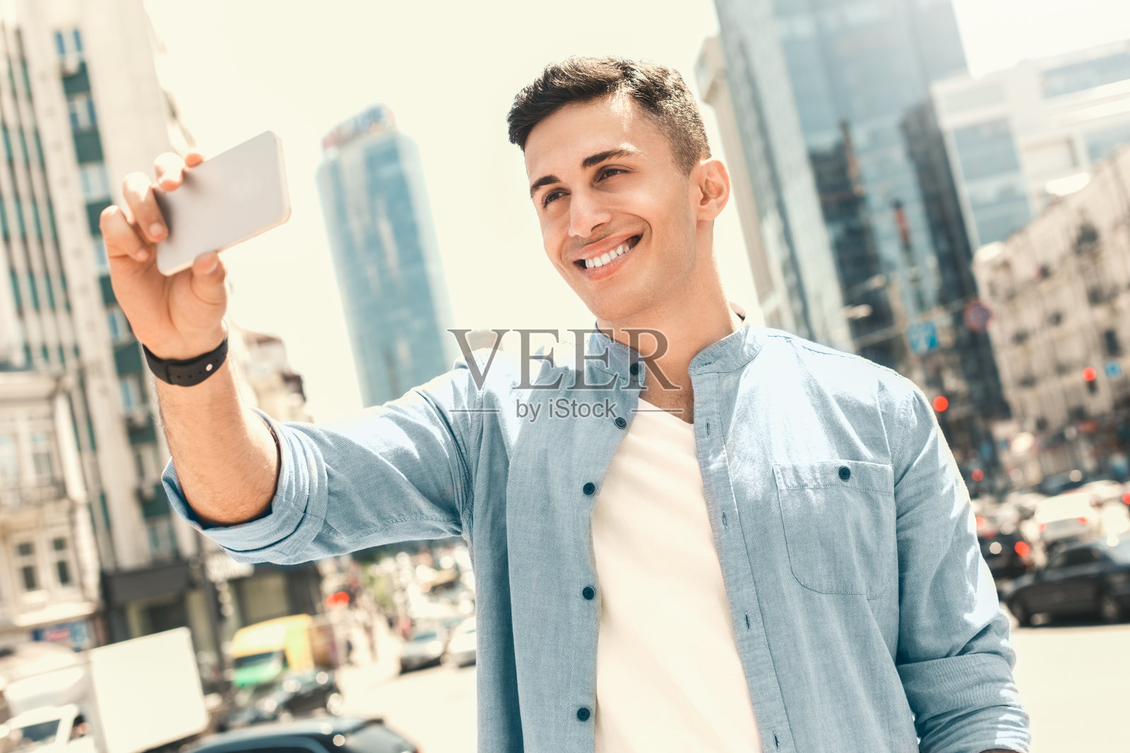 户外休闲。时髦的家伙站在街上拍自拍，笑得很开心照片摄影图片