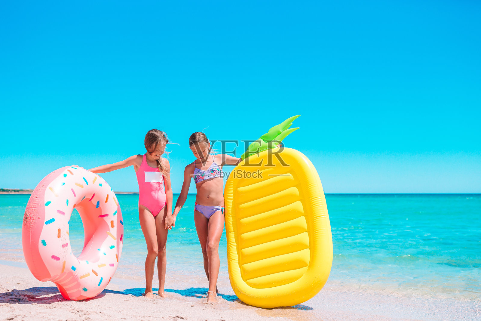 暑假期间，小女孩们在热带海滩一起玩耍照片摄影图片