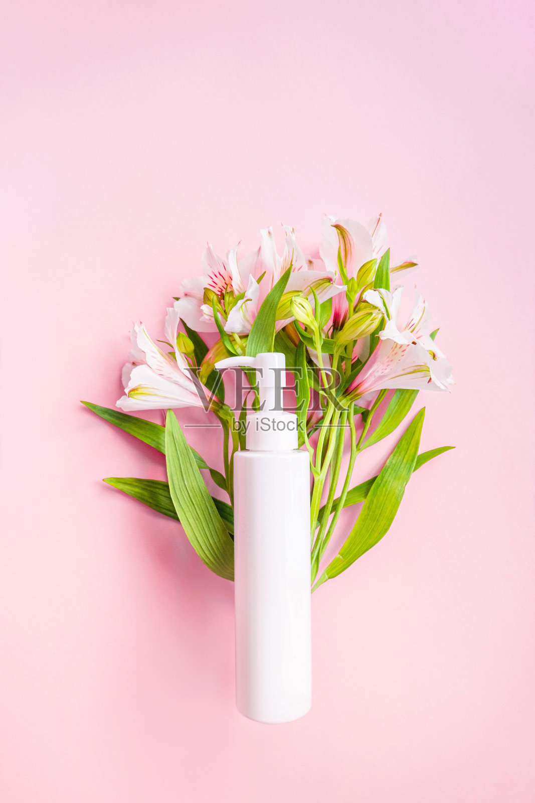 化妆品瓶与分配器与花束花在粉红色的背景。杂志页面风格。化妆品海报或横幅设计。新的现代壁纸。广告横幅。静物的广告照片摄影图片