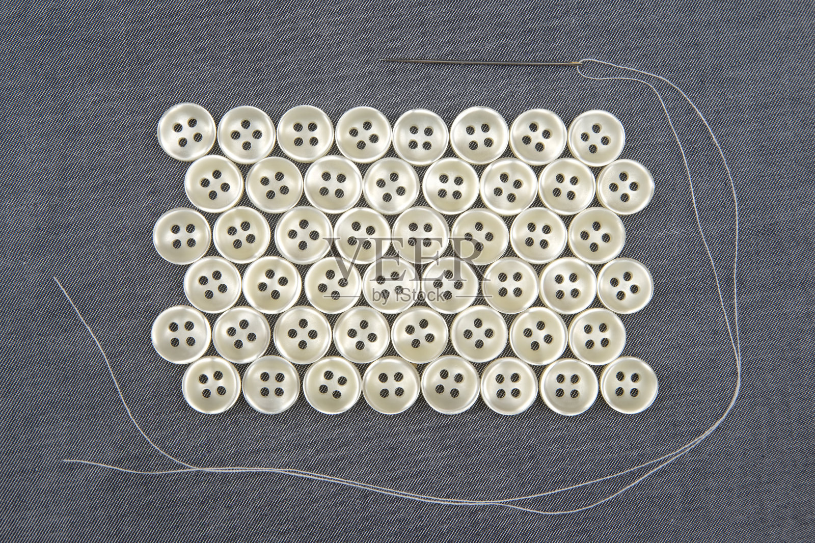缝纫针。布料背景上衣服的塑料闪亮纽扣。时尚和服装。工厂的产业。照片摄影图片