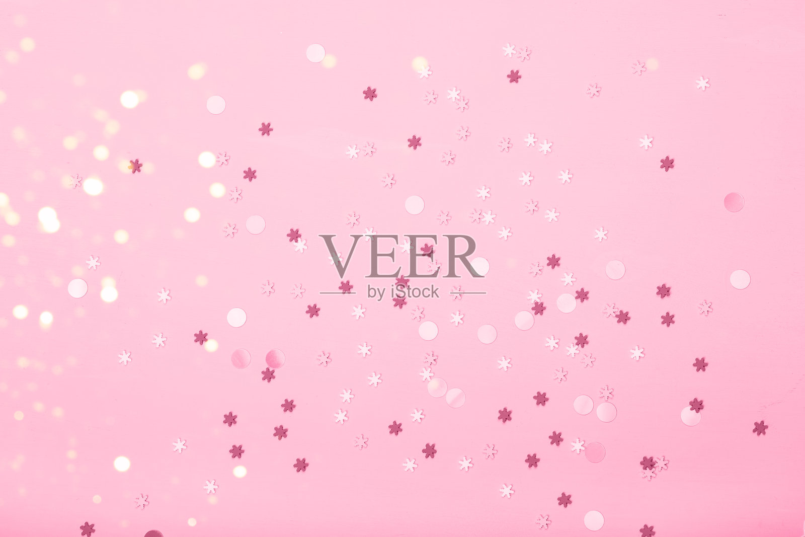 粉红色的背景上点缀着小雪花照片摄影图片