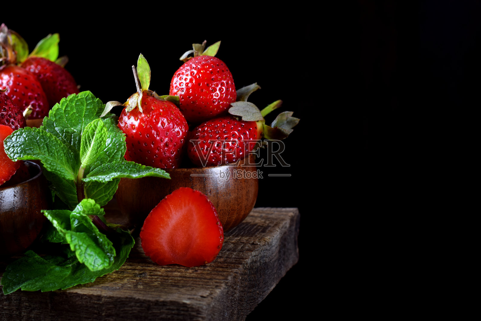 木杯里的成熟草莓放在桌子边上照片摄影图片