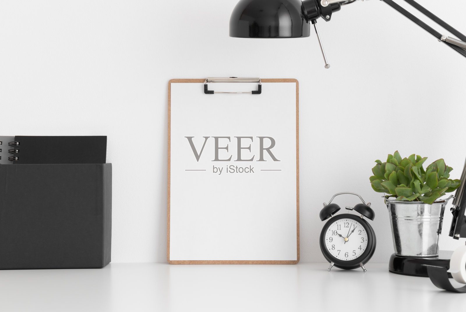 木制的剪贴板模型，一个多汁的锅，灯和工作配件在白色的桌子上。照片摄影图片