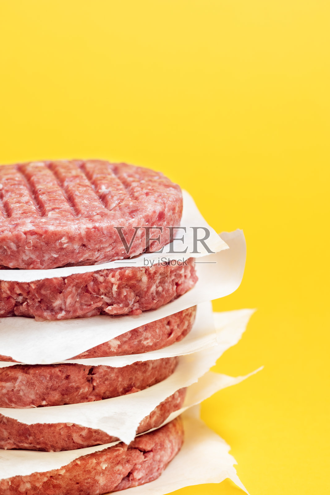 生牛肉饼堆在一个孤立的黄色背景。汉堡牛肉饼特写照片摄影图片