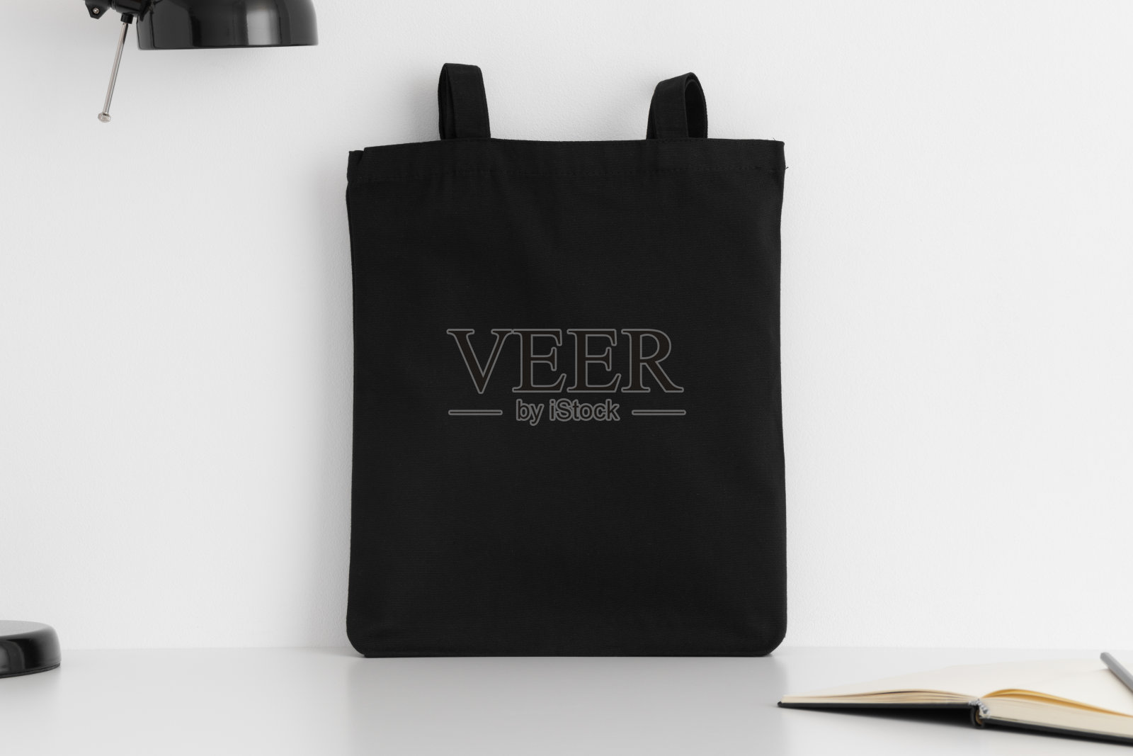 黑色手提袋模型与工作配件在白色桌子上。照片摄影图片