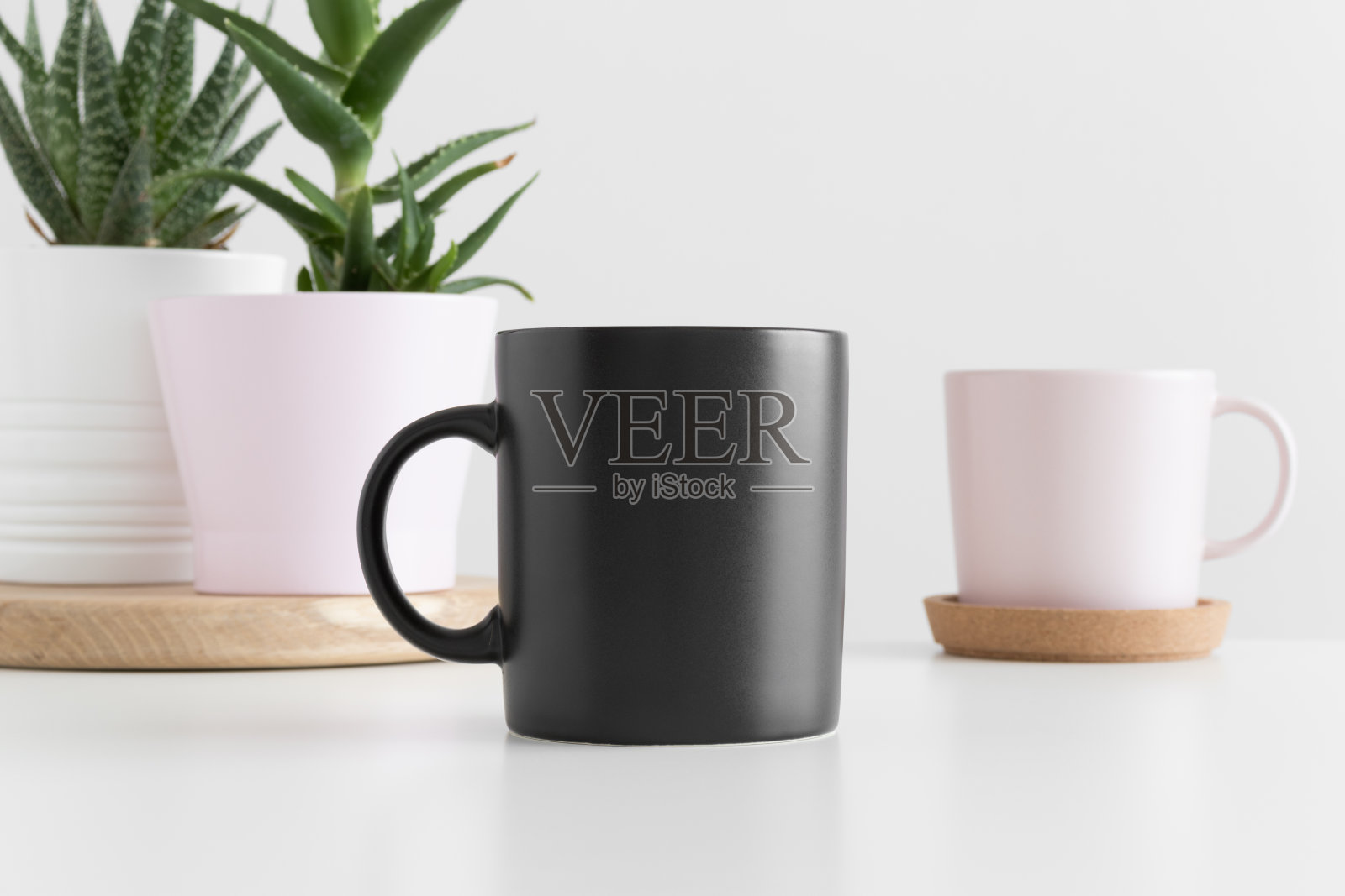 白色的桌子上放着黑色的多肉植物模型杯。照片摄影图片