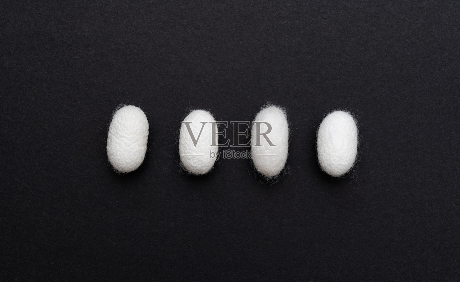 黑色背景上的一排蚕茧照片摄影图片