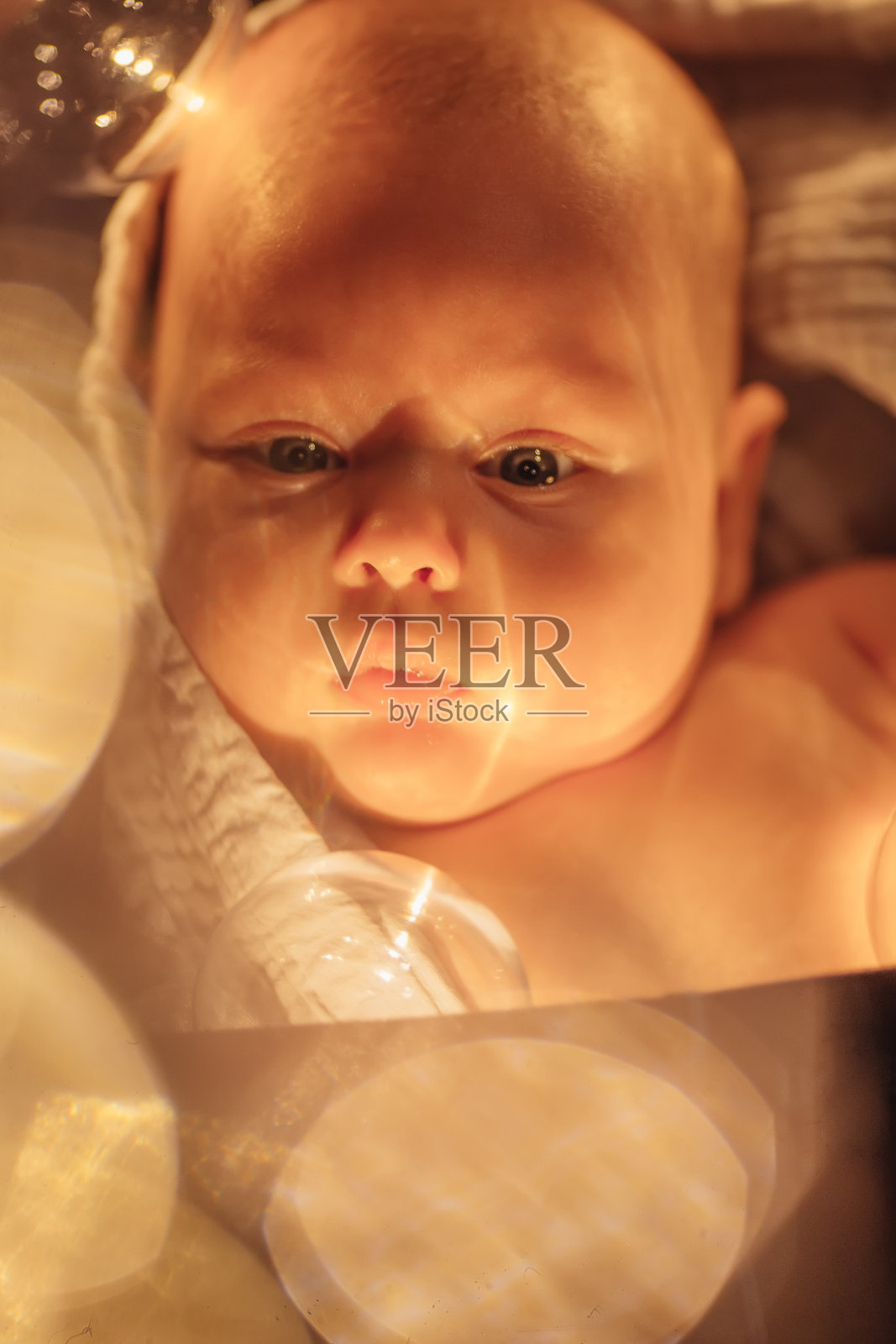 一个漂亮的婴儿的肖像与蓝色的眼睛和棕色的头发闪烁的光照片摄影图片