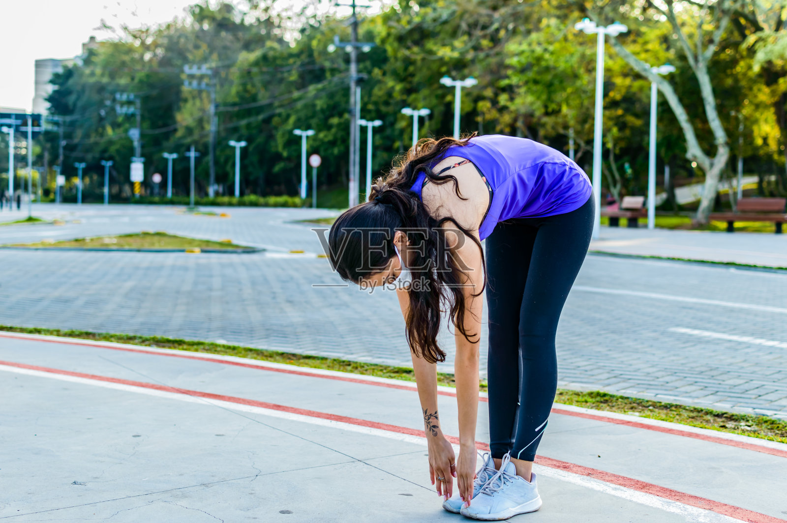 一个戴着面具的年轻女人在新常态下做户外伸展运动照片摄影图片