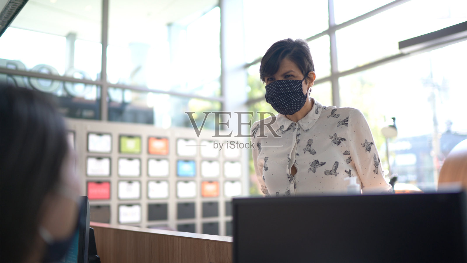 商务人士在办公室大堂入口处与接待员交谈——戴着口罩照片摄影图片