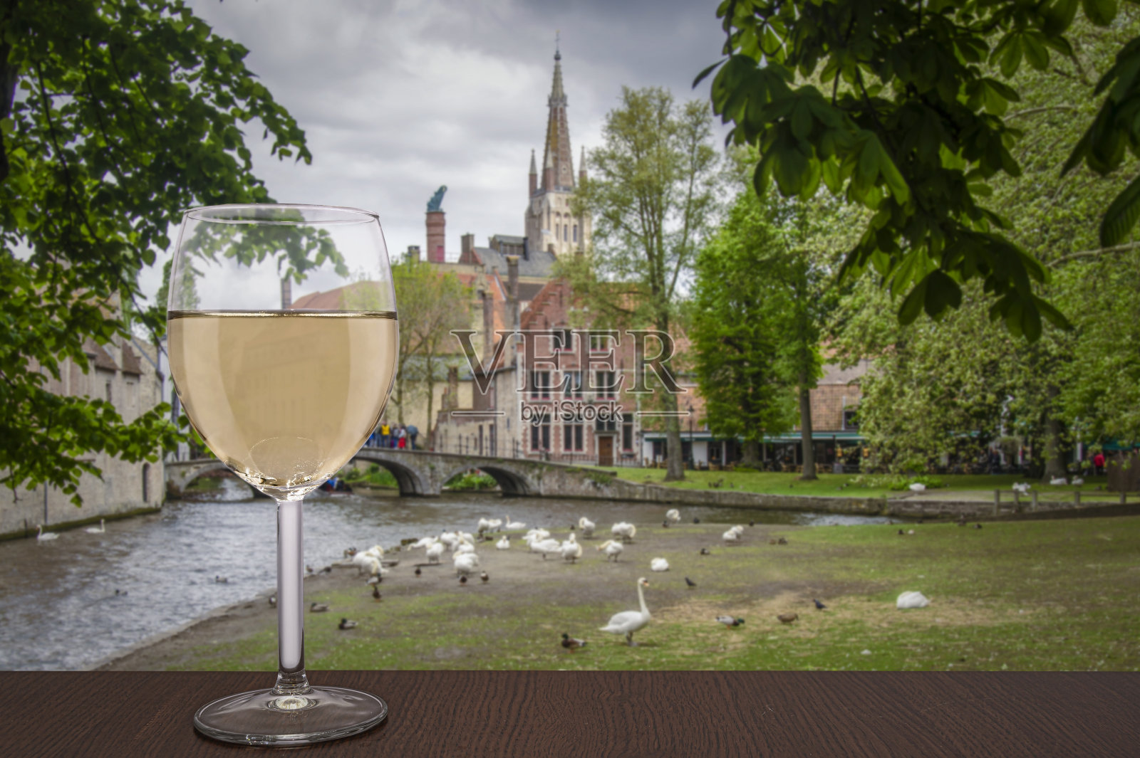 在比利时布鲁日，一杯白葡萄酒。布鲁日的天鹅公园和历史古城。照片摄影图片