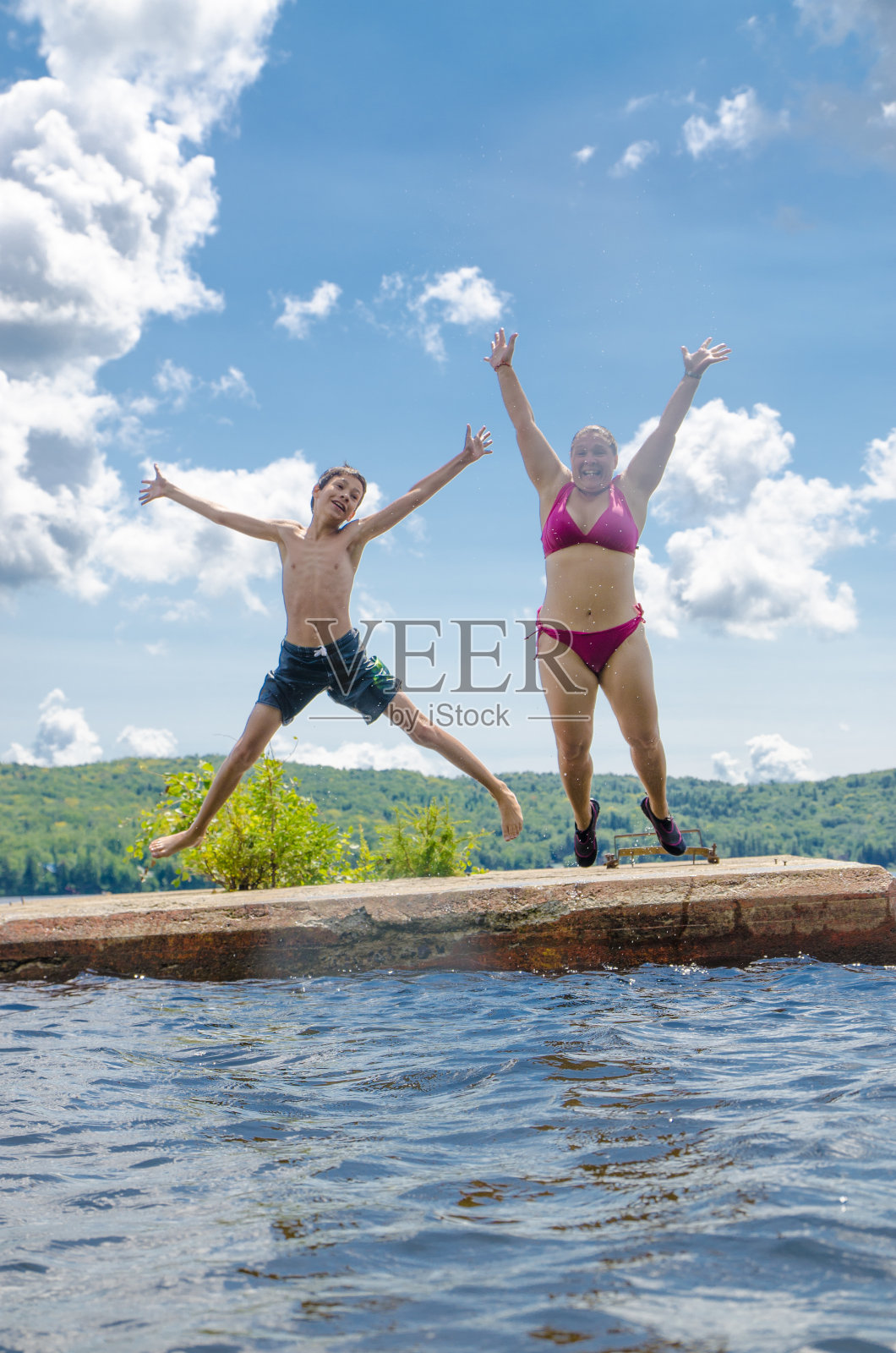男孩和女人在水潭里跳水照片摄影图片