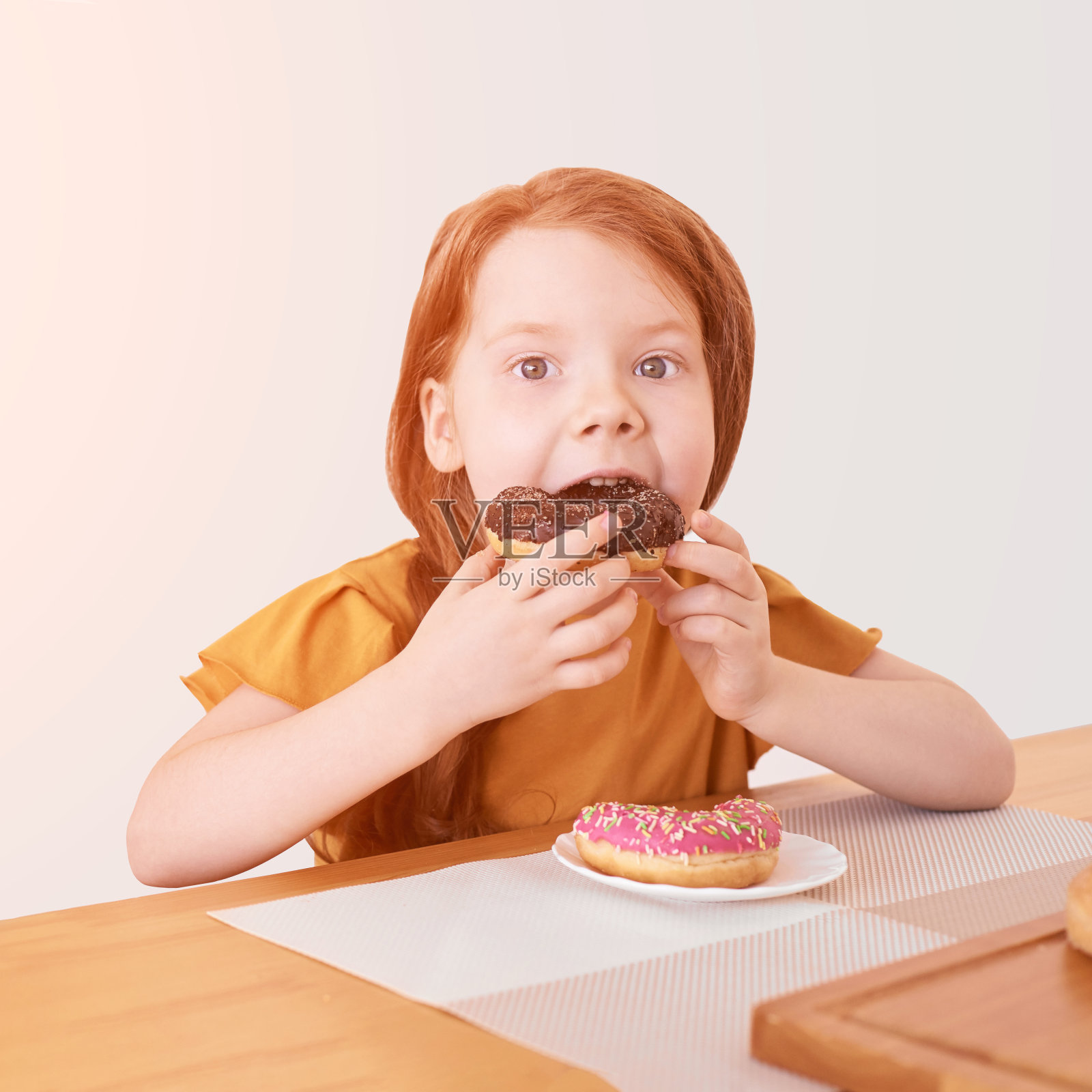 小女孩正在吃圆形甜甜圈。甜蜜的沙漠。不健康的食物照片摄影图片