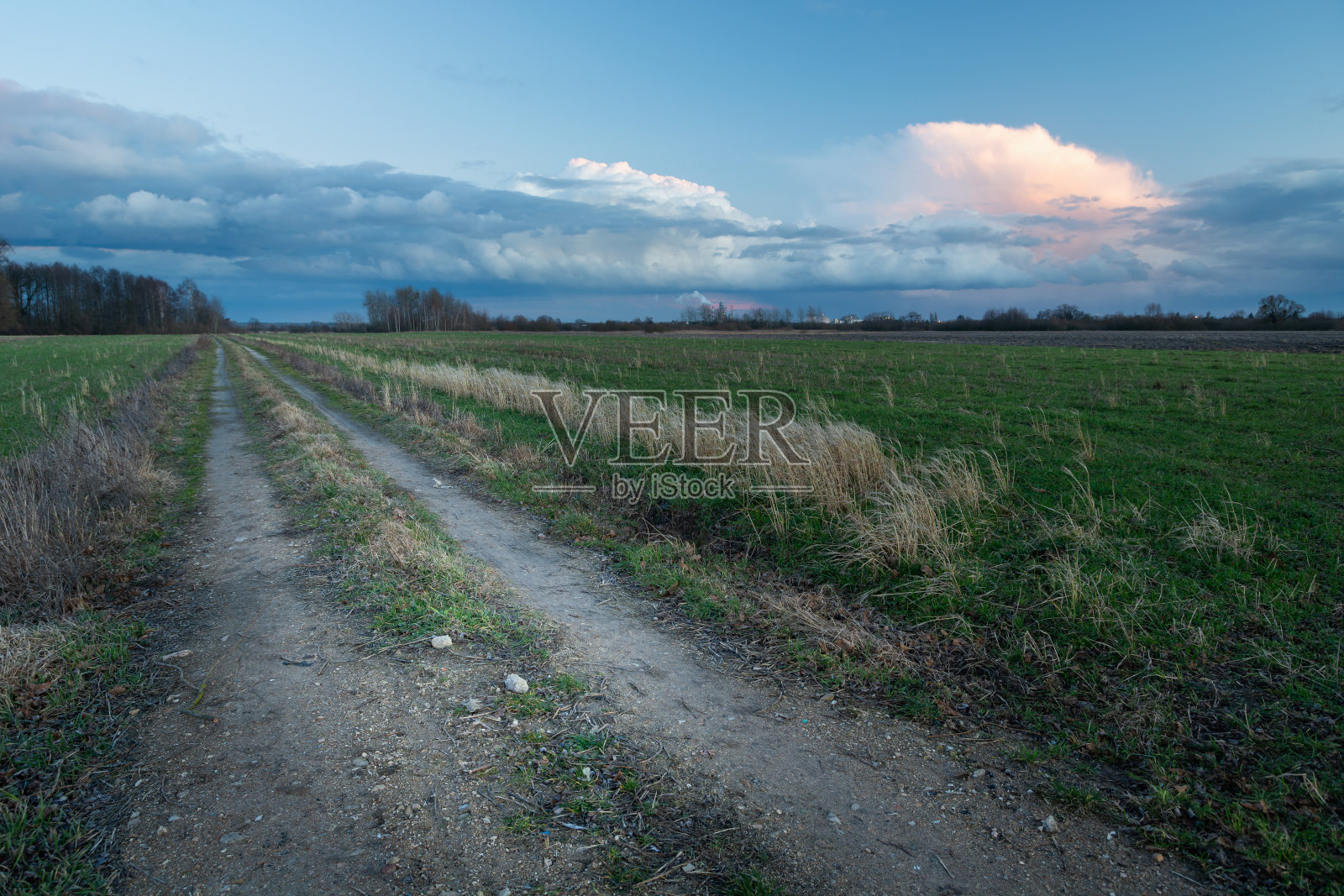 一条穿过田野的土路，傍晚天空中的云朵照片摄影图片