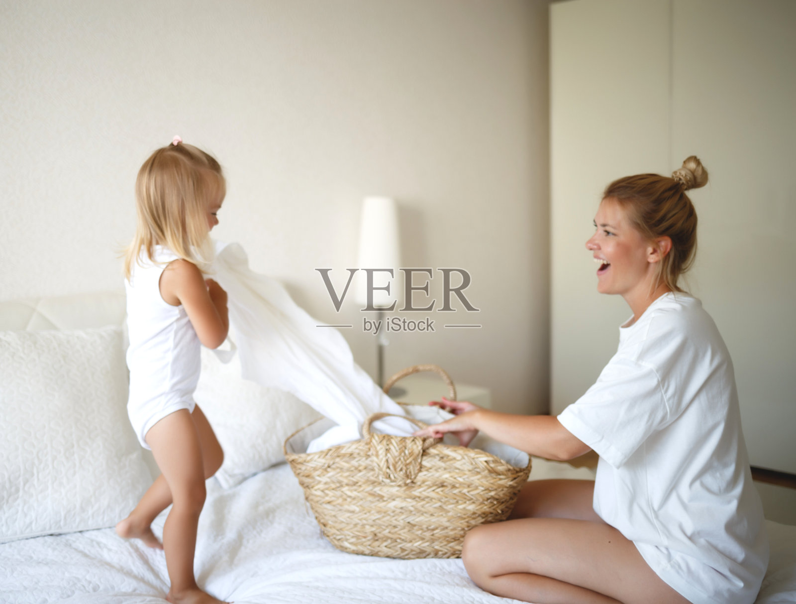 妈妈和女儿拆开一个洗衣的柳条篮子照片摄影图片