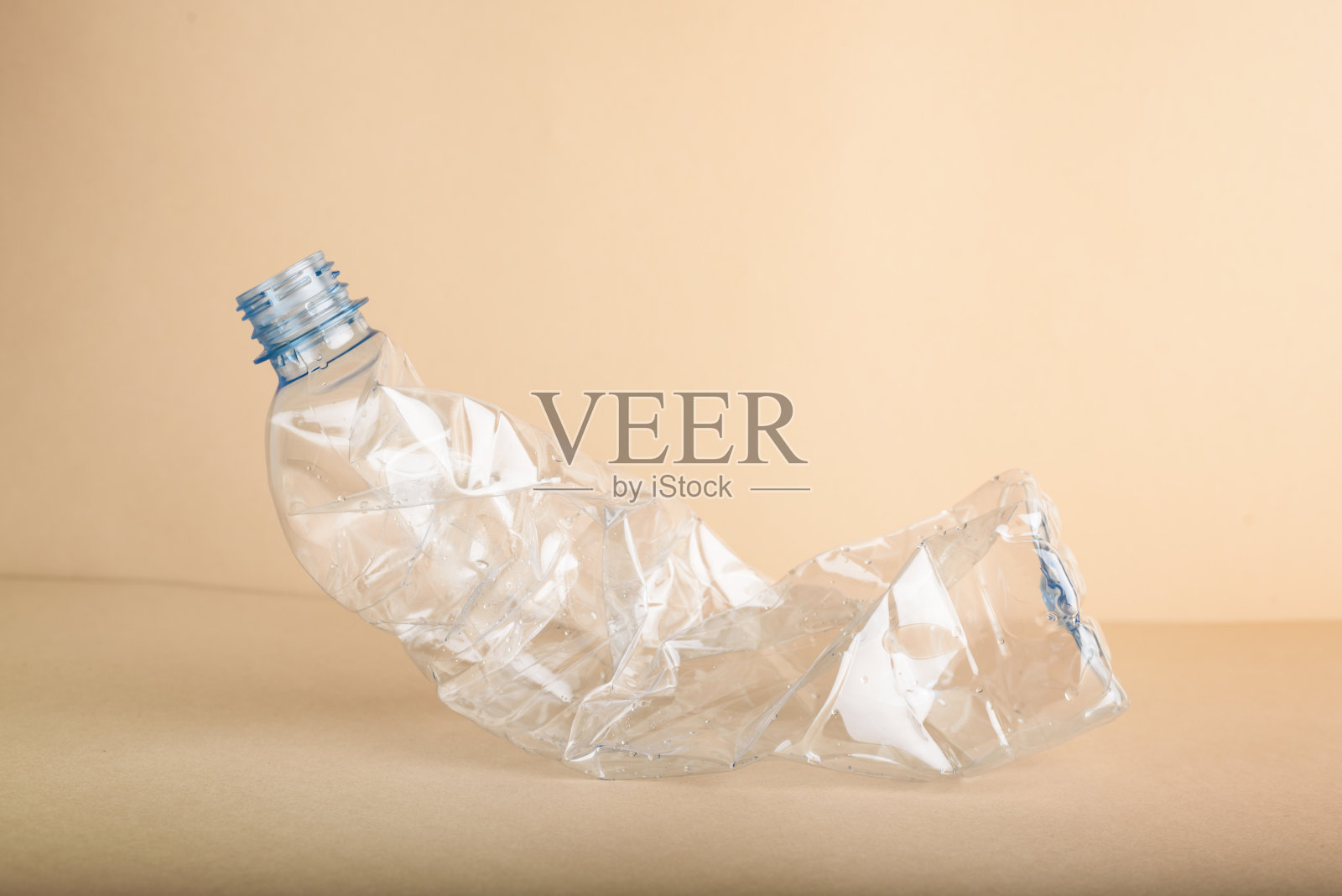 米色背景上使用压碎的塑料瓶。照片摄影图片