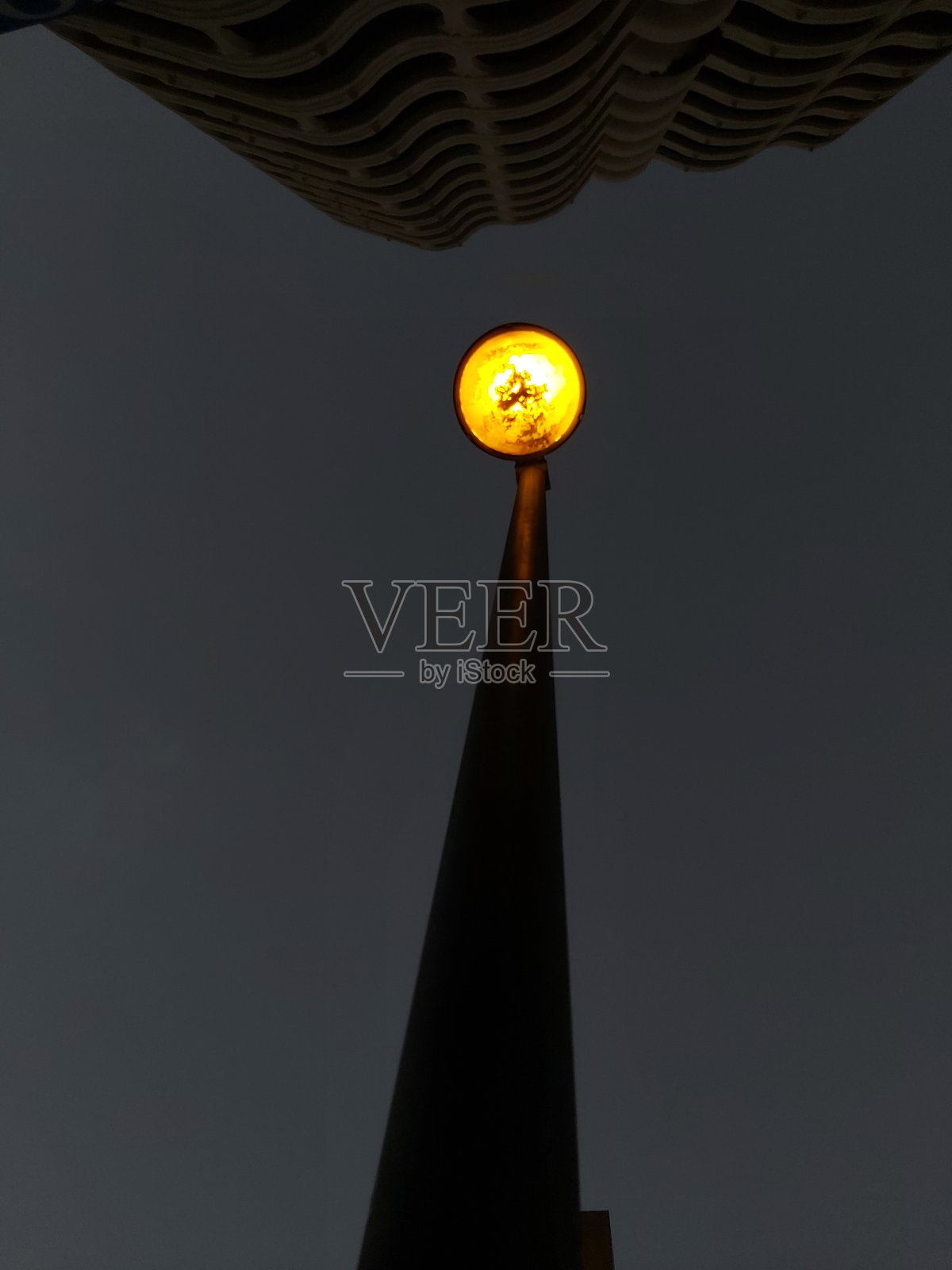 户外路灯。街道照明。路灯与黑暗的天空。黄色的灯和玻璃有点脏和变质。照明位于马拉加市中心。照片摄影图片