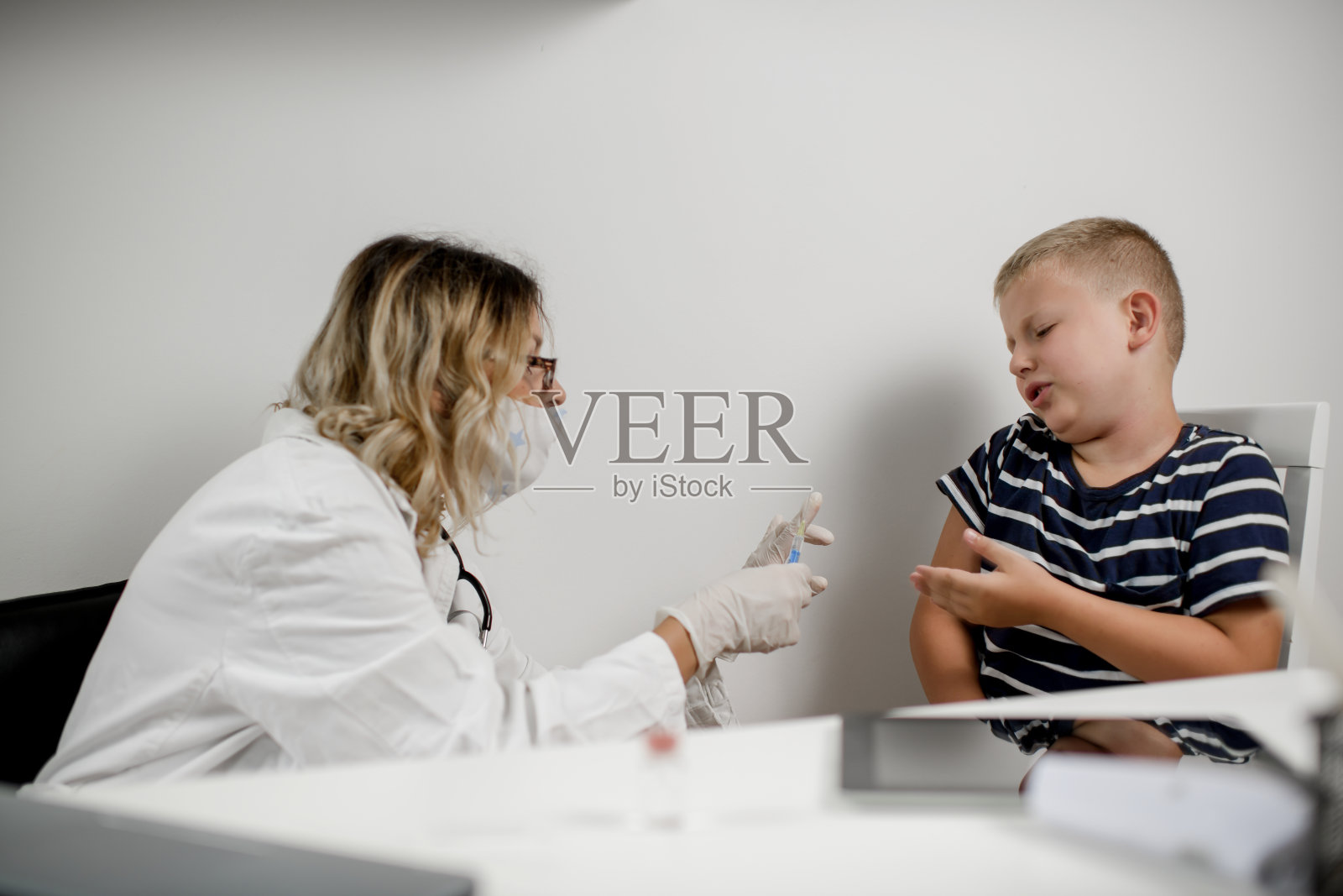 小儿科医生给可爱的白人男孩接种疫苗。照片摄影图片