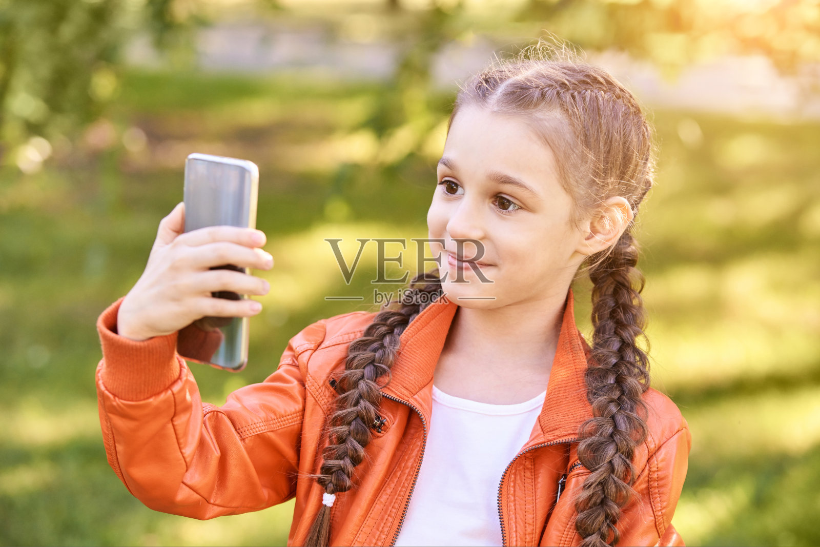 小女孩在自拍。快乐漂亮的孩子。绿色的户外背景照片摄影图片