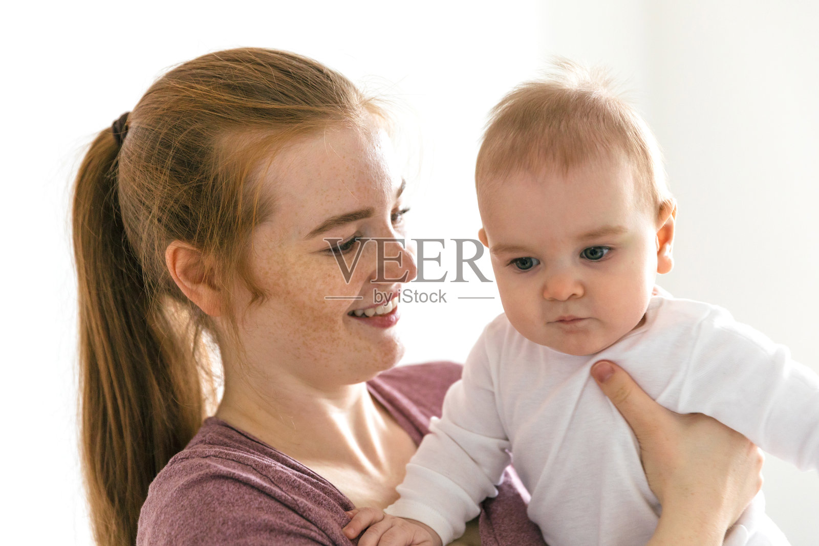 一位年轻的母亲抱着她九个月大的婴儿。快乐的母亲时刻照片摄影图片