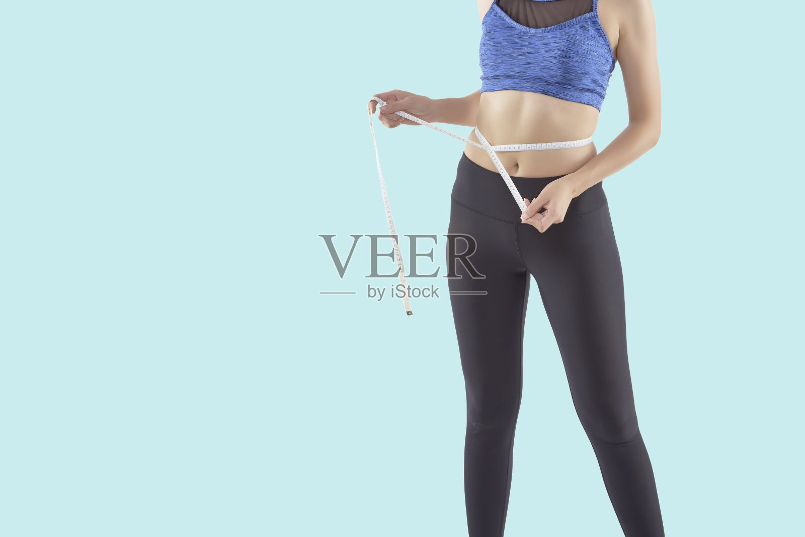 身材匀称的女人在量她的腰围照片摄影图片