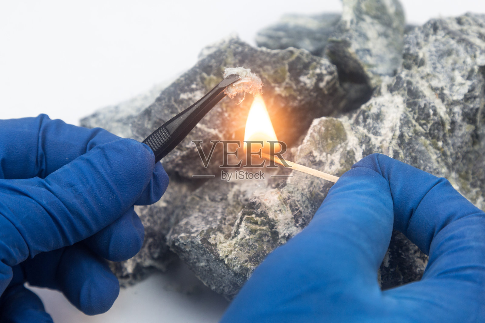 石棉纤维在燃烧的火柴上。照片摄影图片