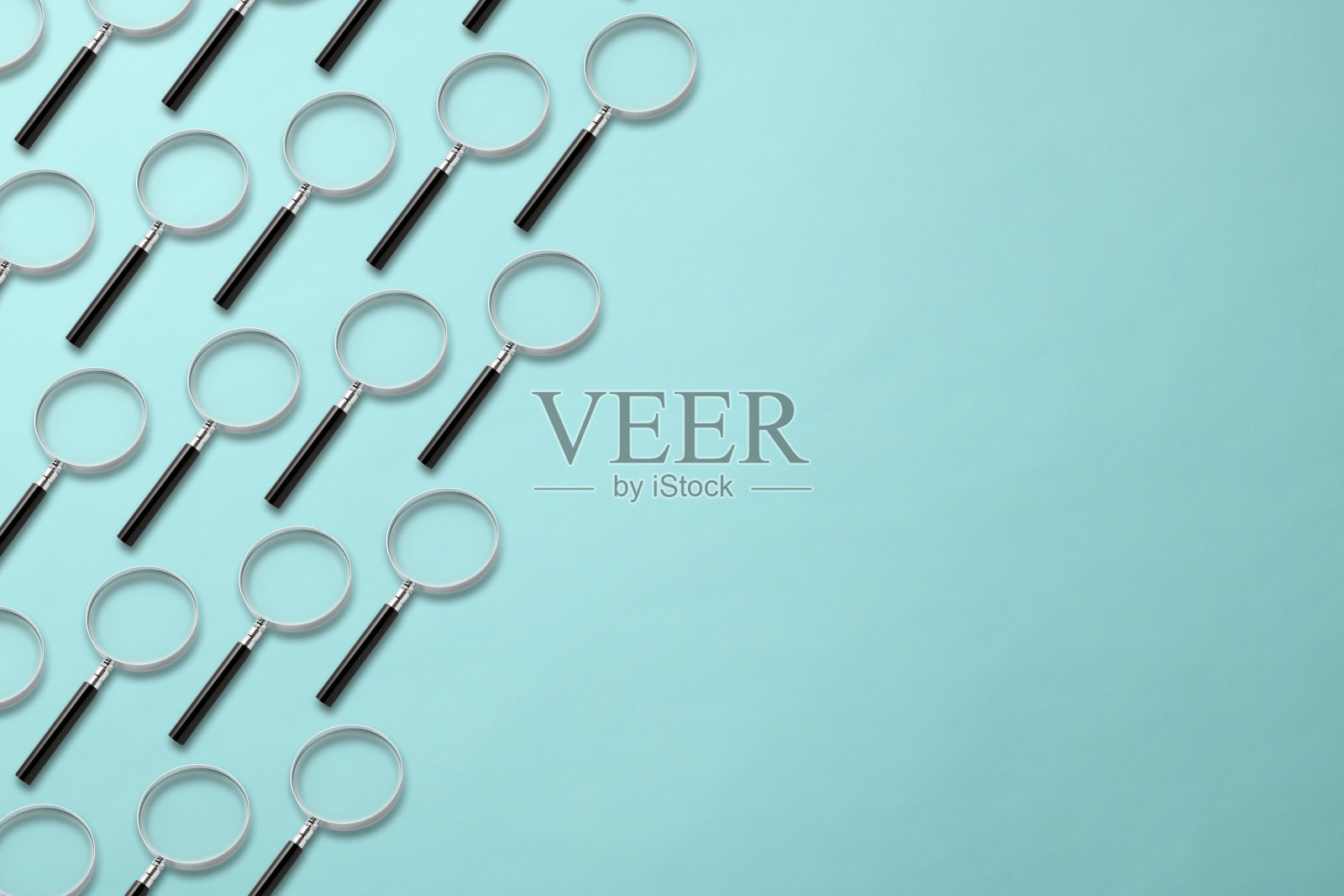 许多放大镜在浅蓝色的背景上排成一行。照片摄影图片