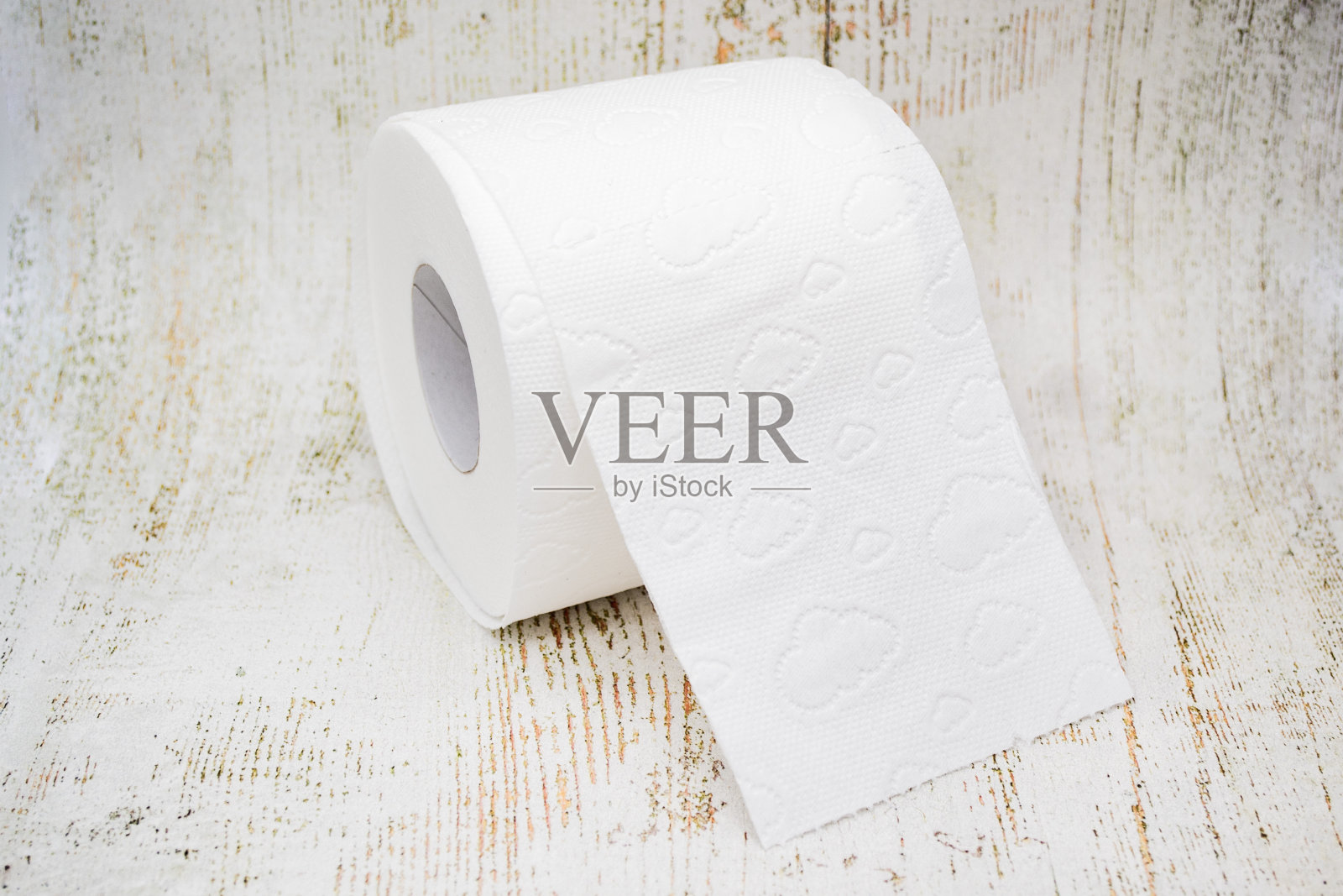 一卷带有穿孔的白色厕纸，背景是老化的浅色木材照片摄影图片
