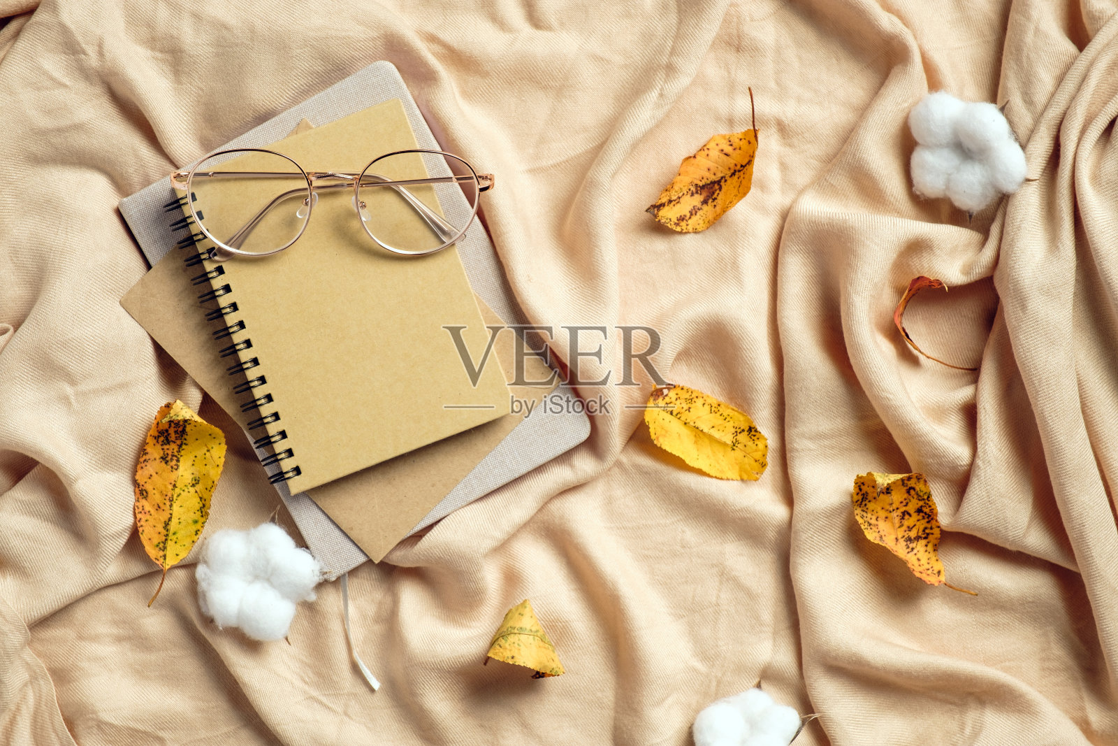 秋平铺构成。纸笔记本，眼镜，棉布和干树叶米色格子。秋季hygge风格的书桌桌子照片摄影图片