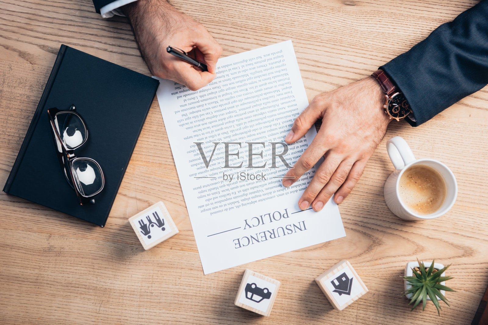 俯视图律师签署保险单协议附近的工厂，眼镜，笔记本和木制立方体与家人，汽车和房子照片摄影图片