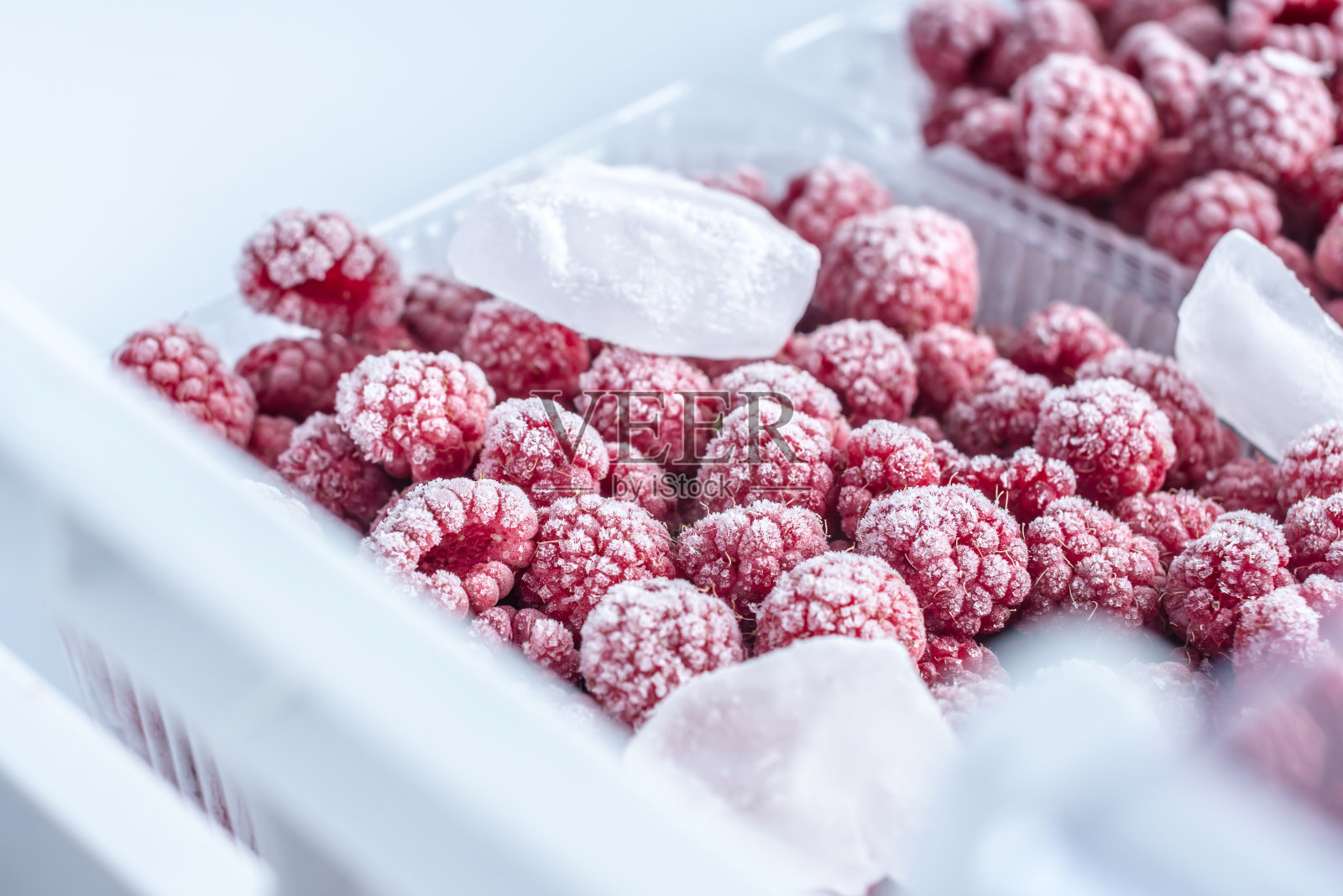 冷冻树莓的容器放在冰箱的冰柜里。冷冻食品的概念，长期储存产品照片摄影图片