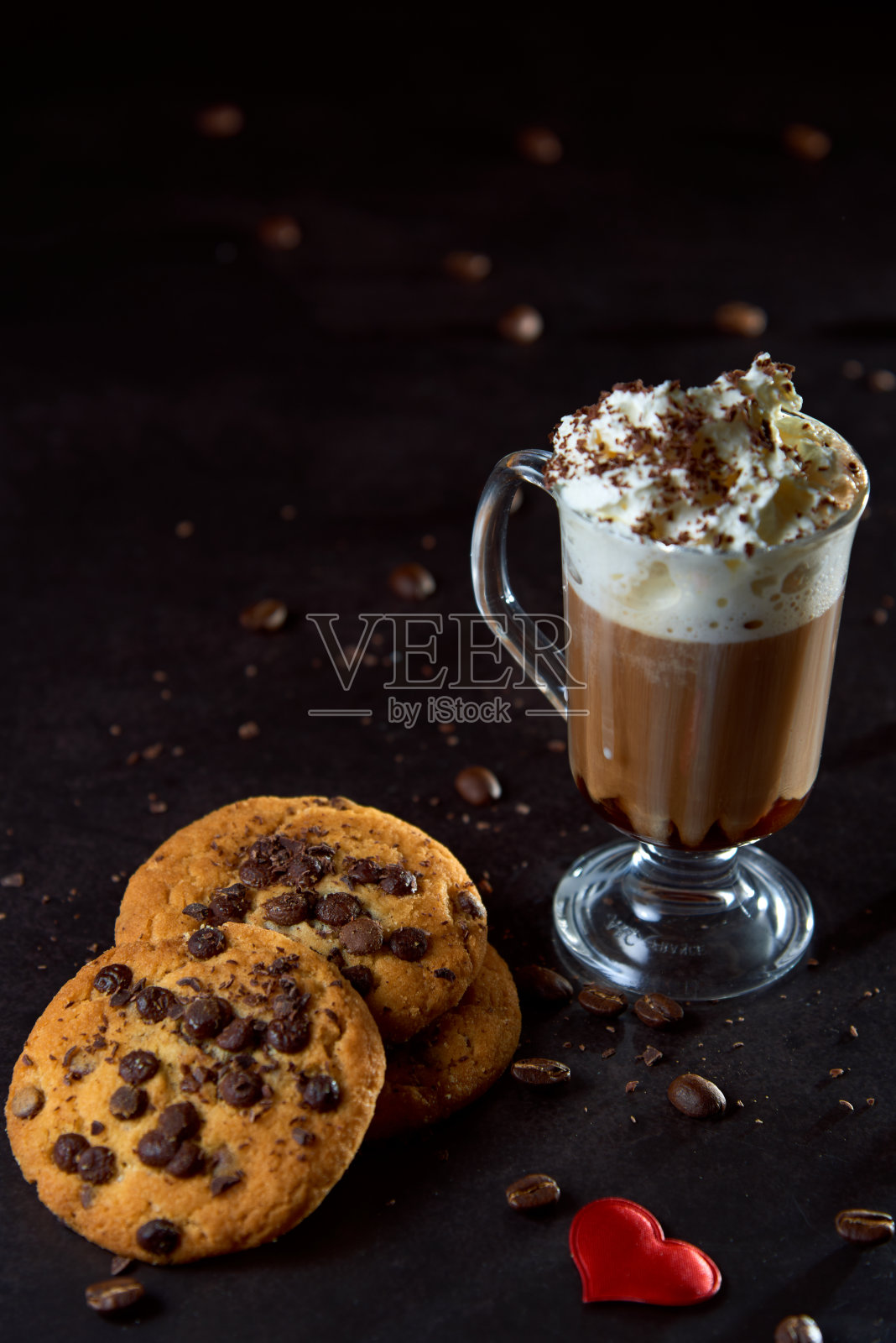 近距离的一杯咖啡与掼奶油和巧克力屑在它上，巧克力饼干和roastedÂ coffeeÂ豆在黑暗的背景。概念即食食品，美味小吃。选择性聚焦，复制空间。照片摄影图片