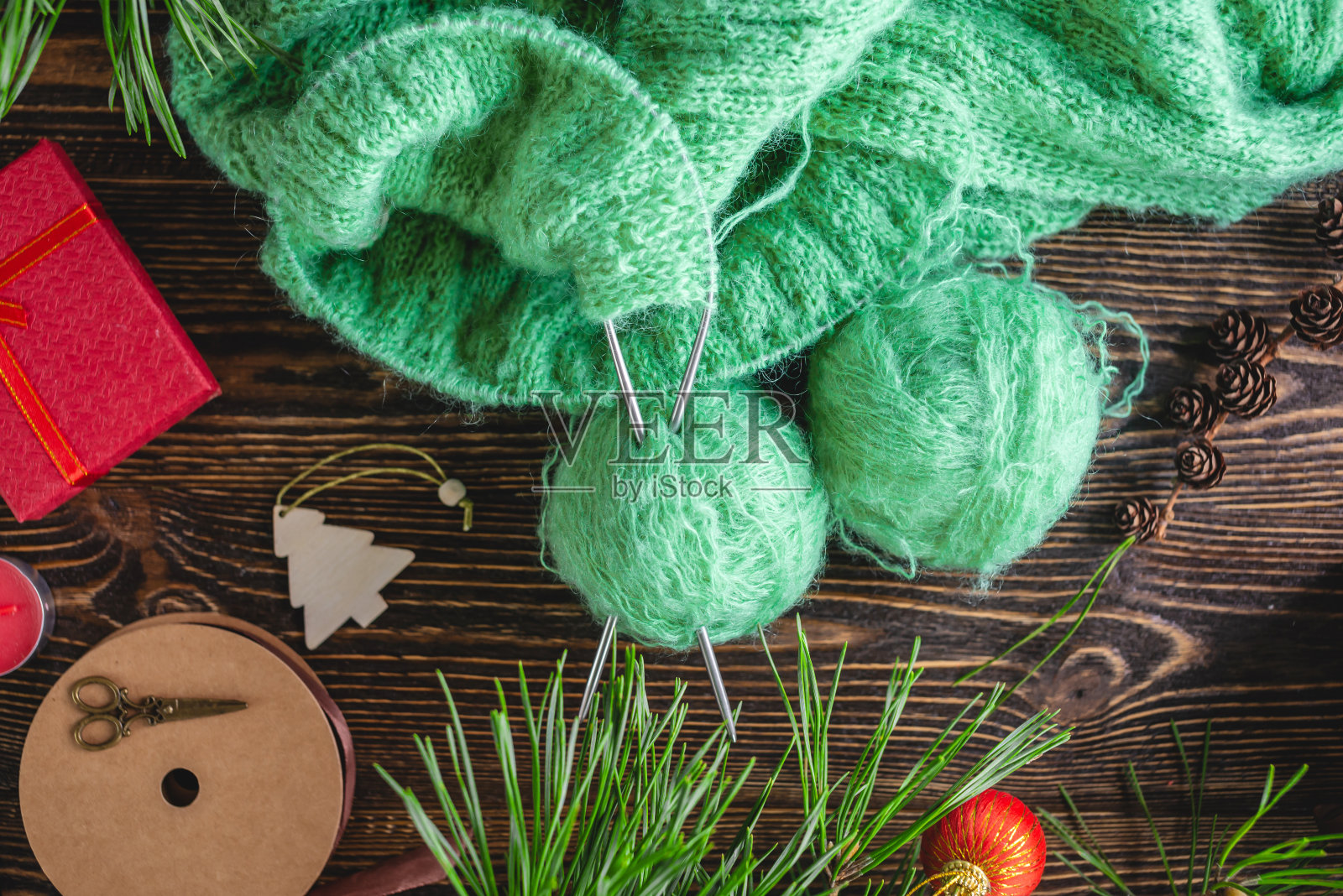 温暖舒适的毛衣在编织的过程中在针上。创造新年和圣诞节手工礼物的概念照片摄影图片