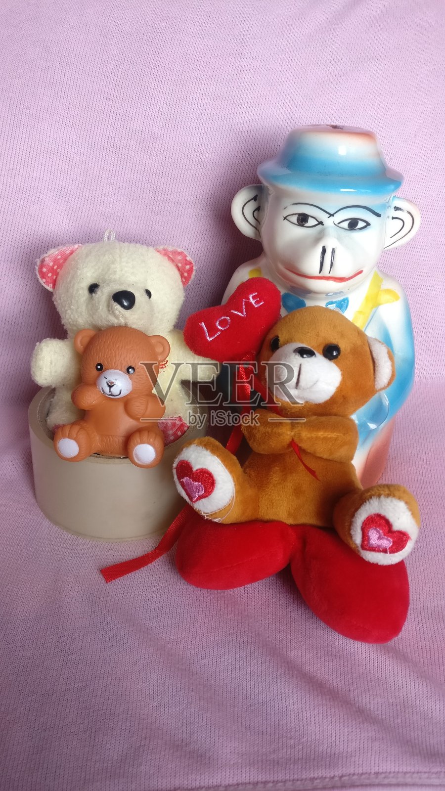 红色橙色和棕色的泰迪熊玩具与陶瓷猴猿帽子照片摄影图片