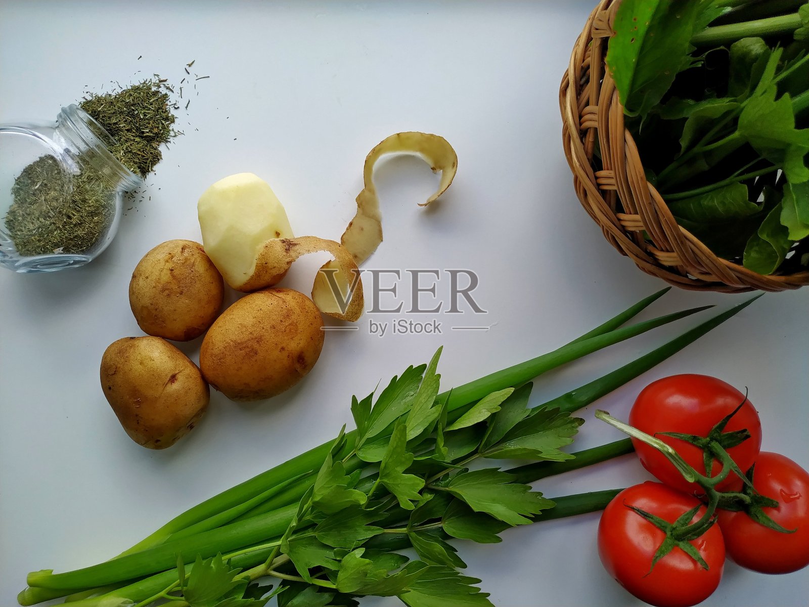 白色的桌子上放着嫩土豆，新鲜的芹菜，西红柿，青葱照片摄影图片