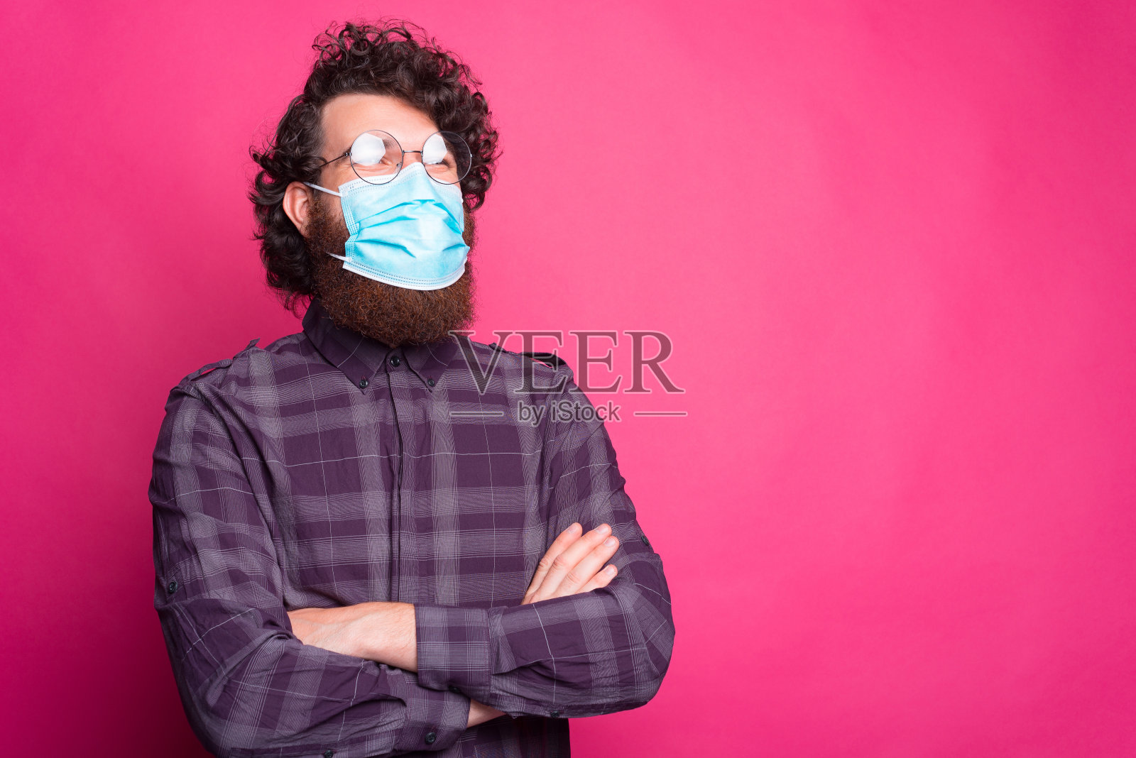 年轻男子的肖像，交叉双臂，戴着医用面具，看向别处照片摄影图片