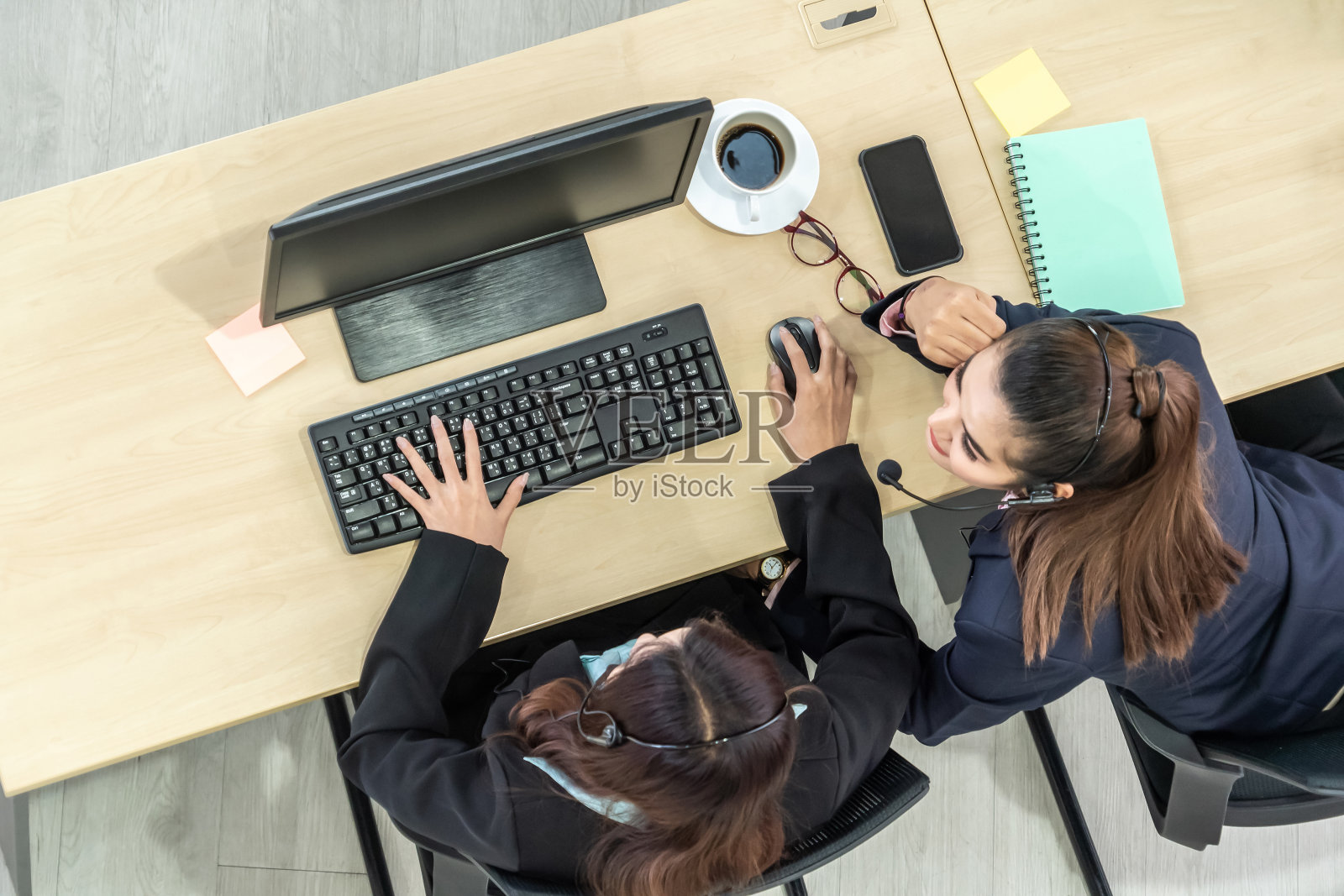 商务人员戴着头戴式耳机在办公室使用电脑工作照片摄影图片