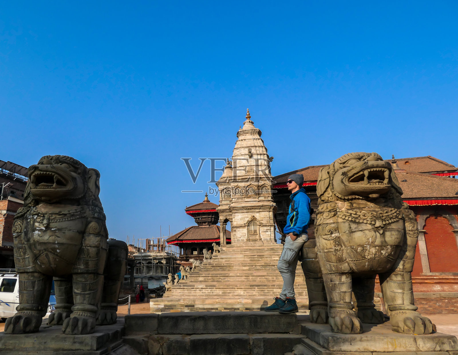 巴克塔布尔-一个人靠在守护狮子和在后面的观塔照片摄影图片