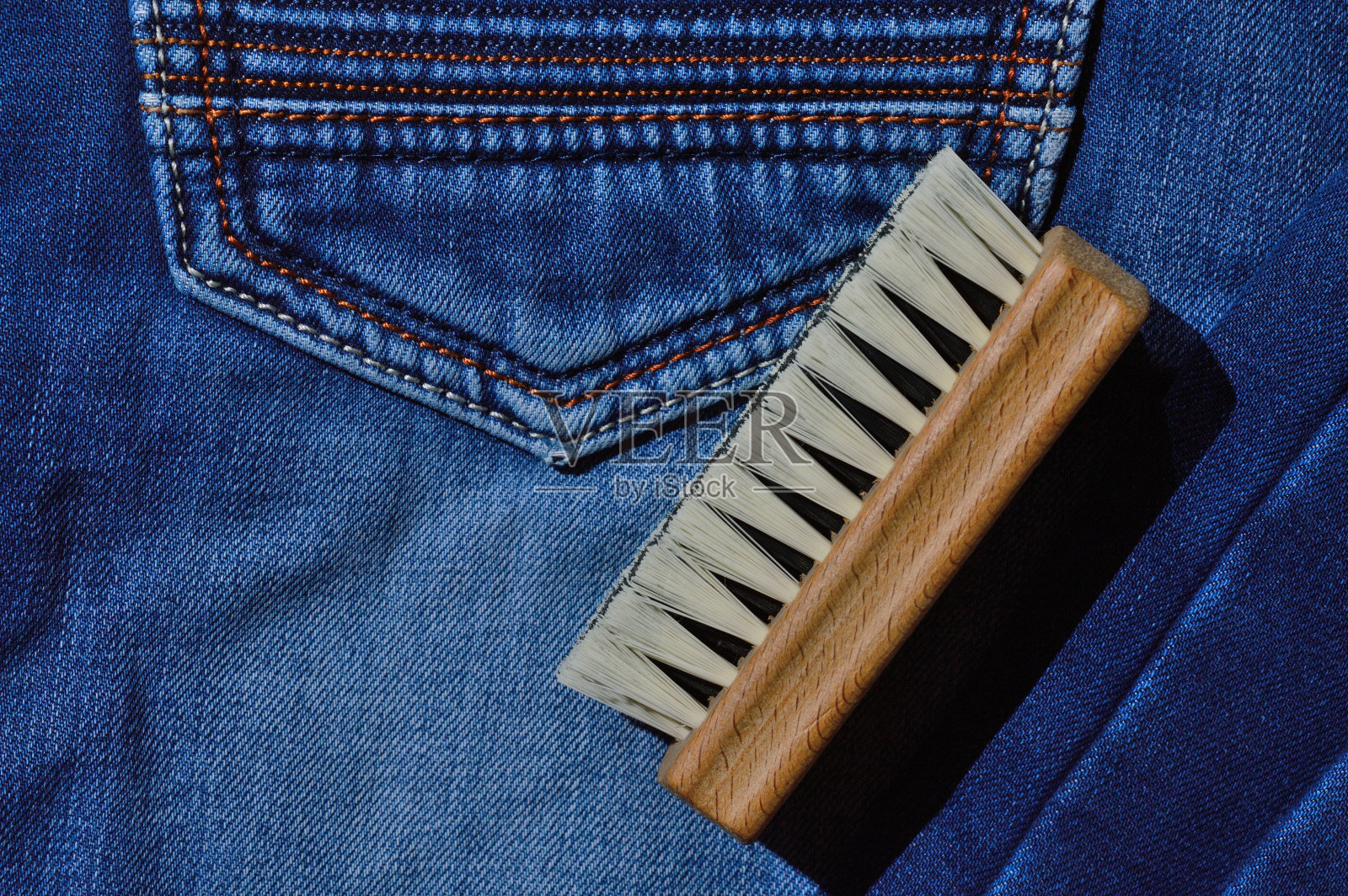 折叠的牛仔裤上放着一把衣服刷。照片摄影图片