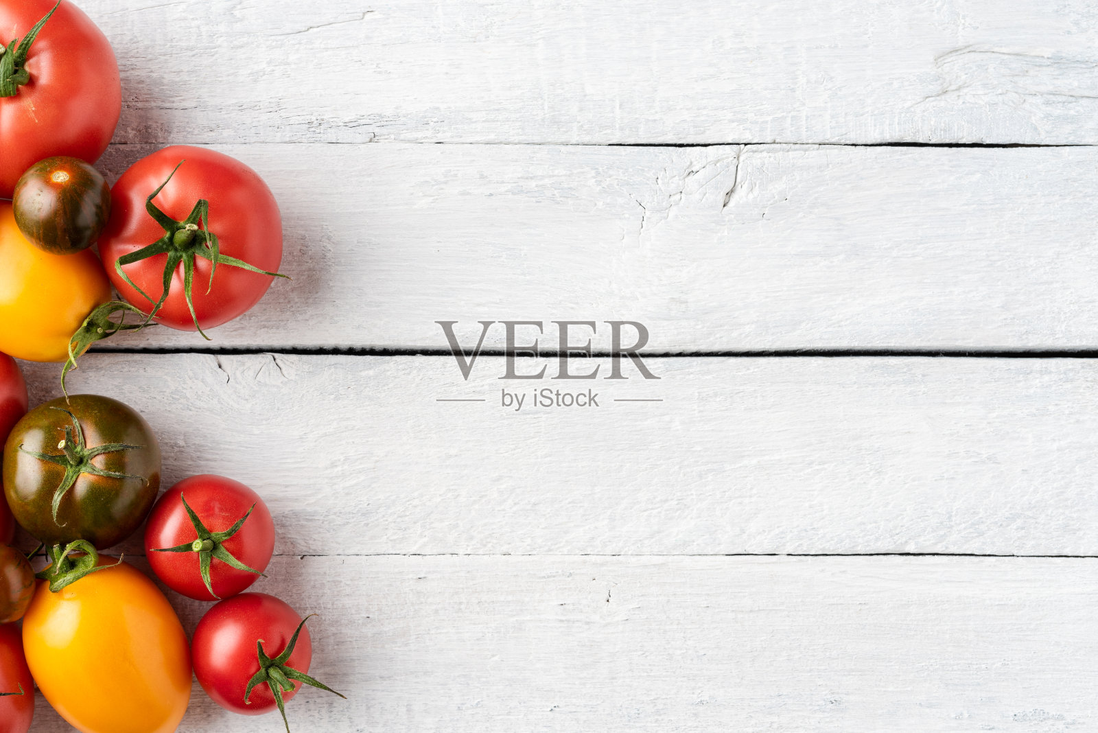 不同的西红柿在白色的木制背景与copyspace。俯视图照片摄影图片