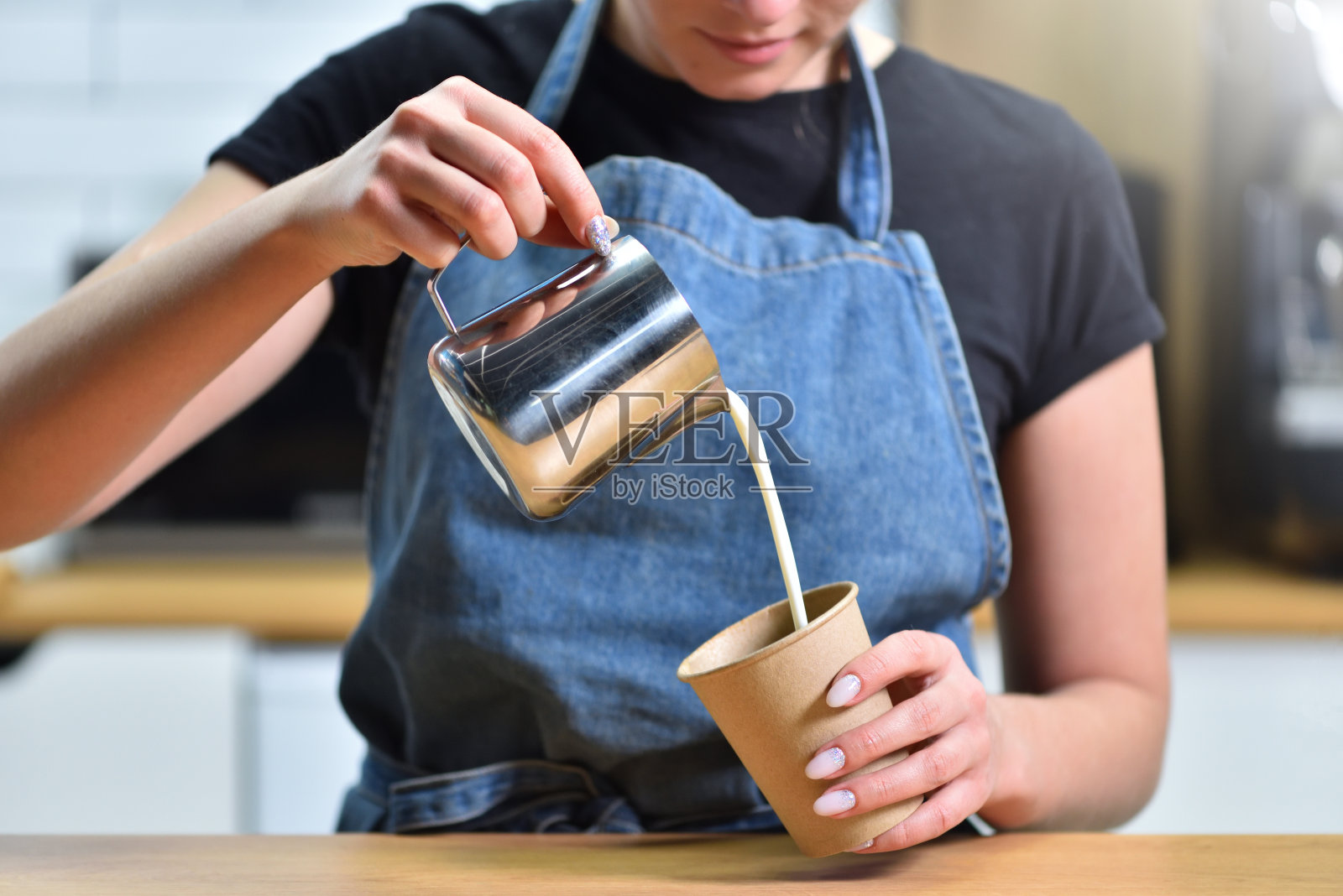 咖啡师制作咖啡，把牛奶倒进一个加了意式浓缩咖啡的纸杯里制成卡布奇诺照片摄影图片