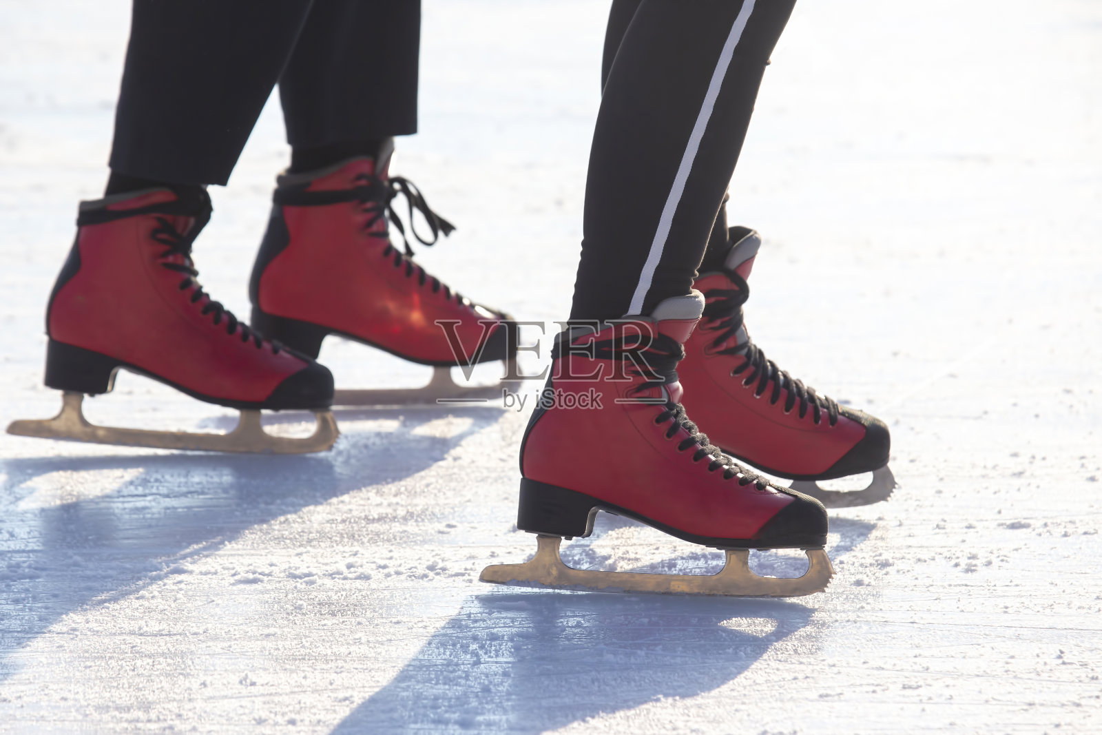 穿着红色溜冰鞋的脚在溜冰场上。爱好和休闲。冬季运动照片摄影图片